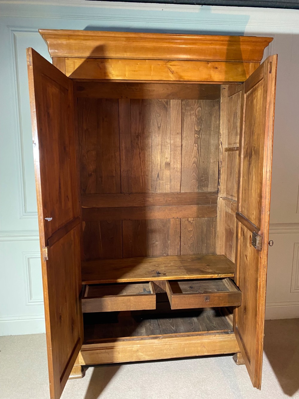 A tall 19th-century cherry wood armoire featuring double panelled doors, decorative iron keyplates, and a projecting upper cornice. View XIV