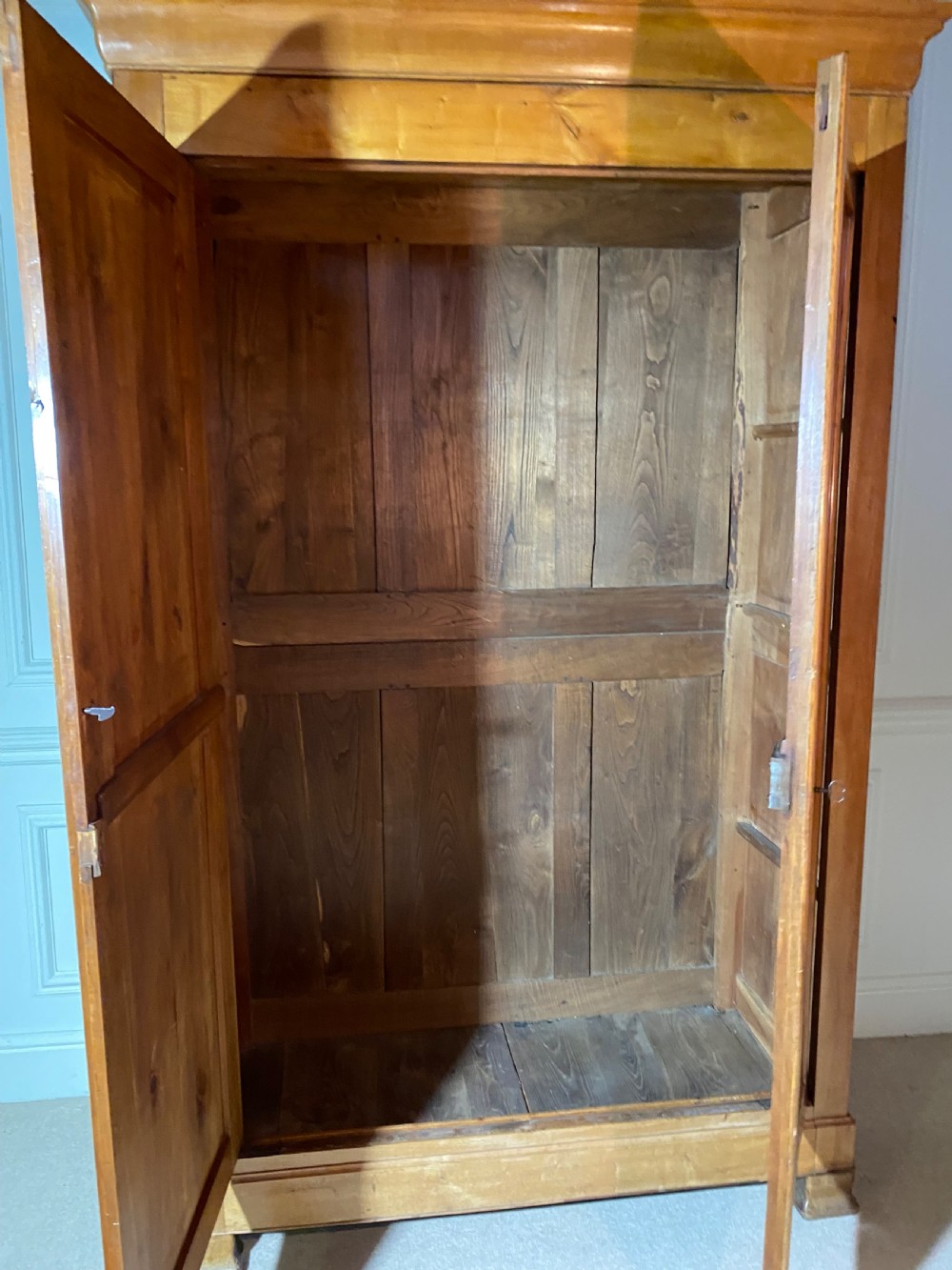 A tall 19th-century cherry wood armoire featuring double panelled doors, decorative iron keyplates, and a projecting upper cornice. View XVI