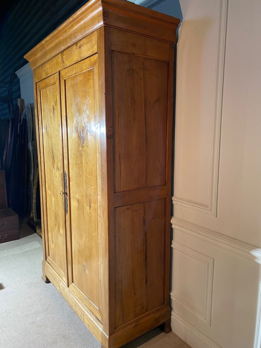 A tall 19th-century cherry wood armoire featuring double panelled doors, decorative iron keyplates, and a projecting upper cornice. View XX