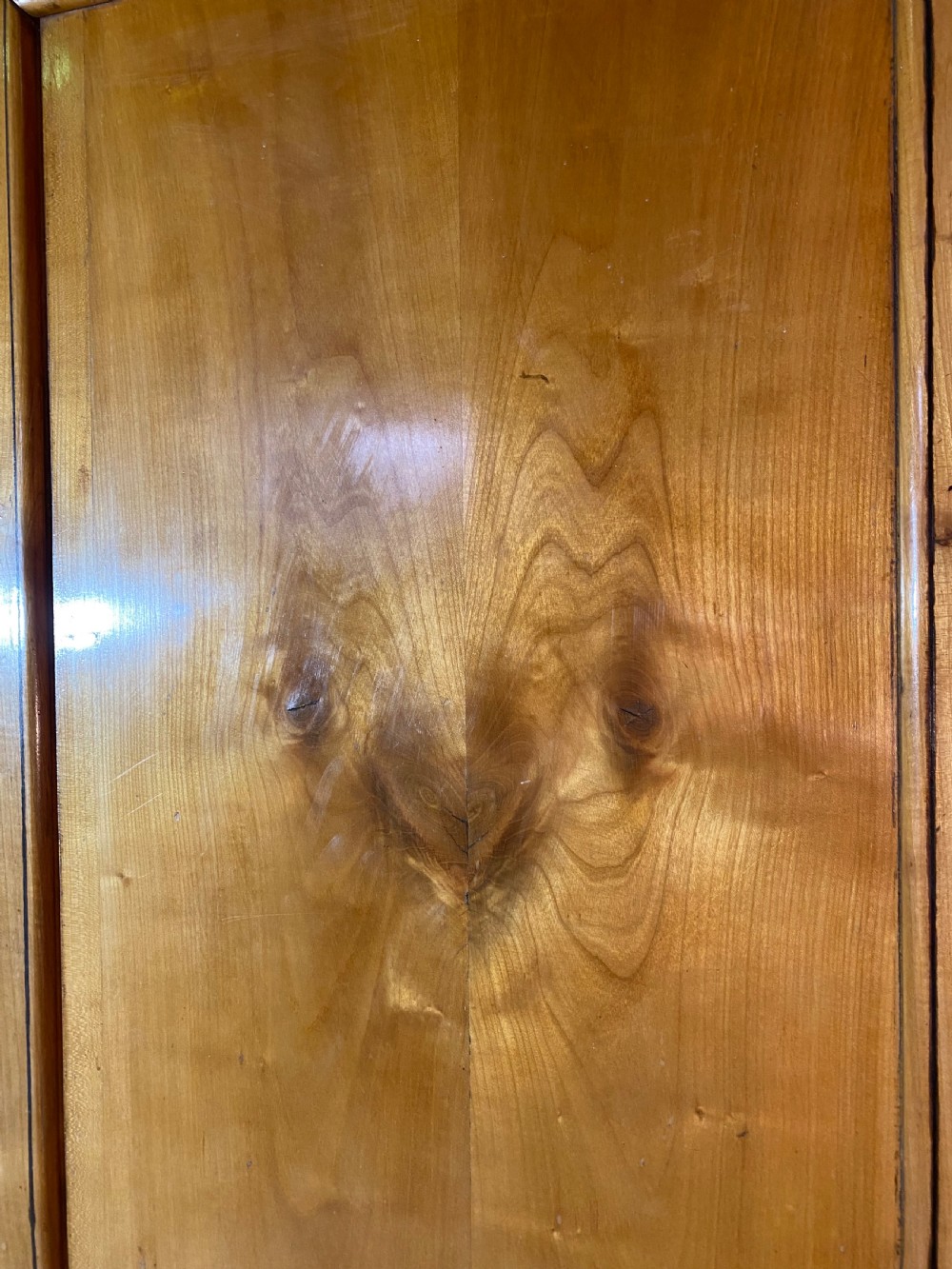A tall 19th-century cherry wood armoire featuring double panelled doors, decorative iron keyplates, and a projecting upper cornice. View XXI