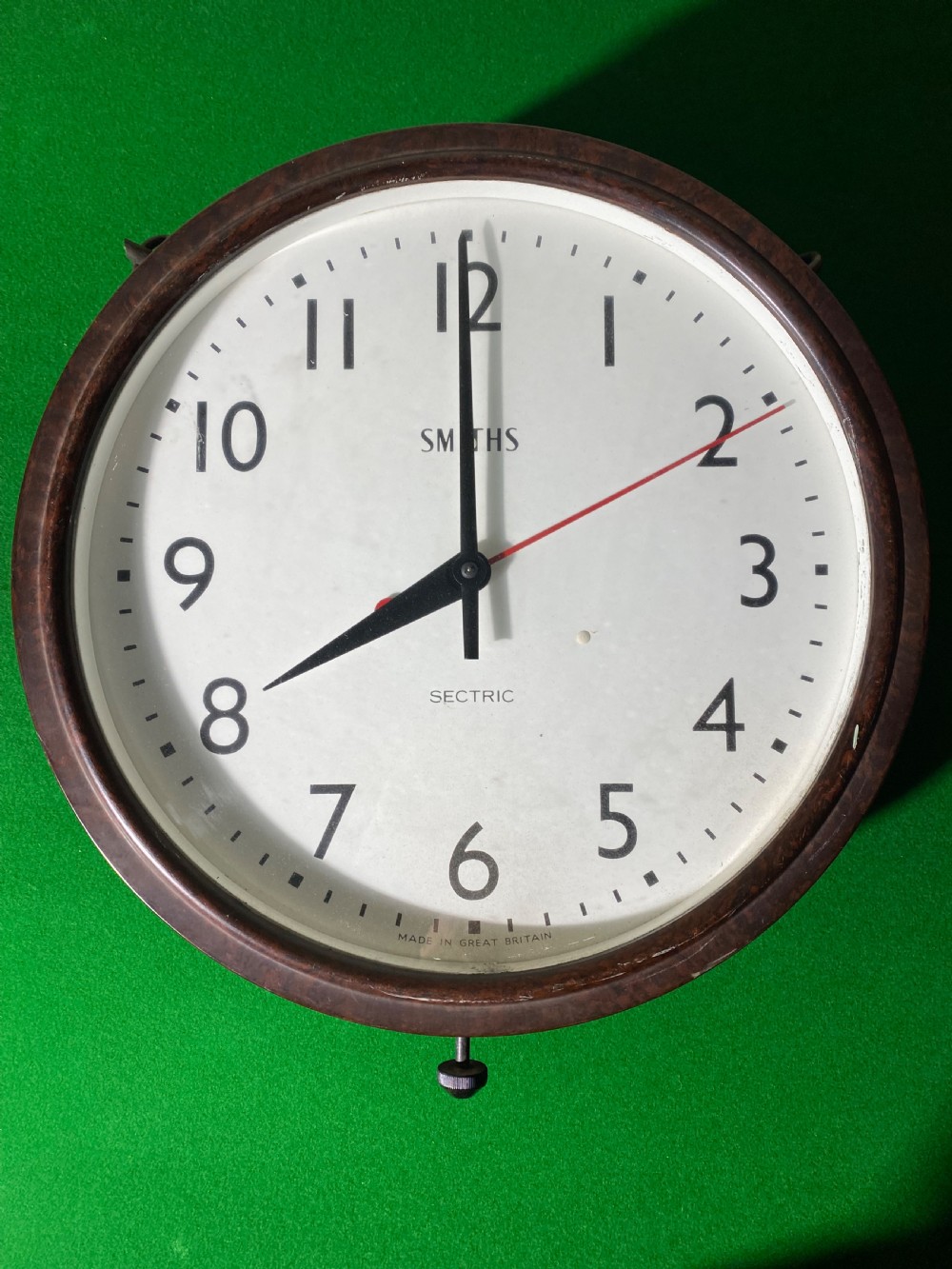 A circular double-sided vintage Smiths Sectric factory clock with a dark brown Bakelite frame and off-white dial face. View II