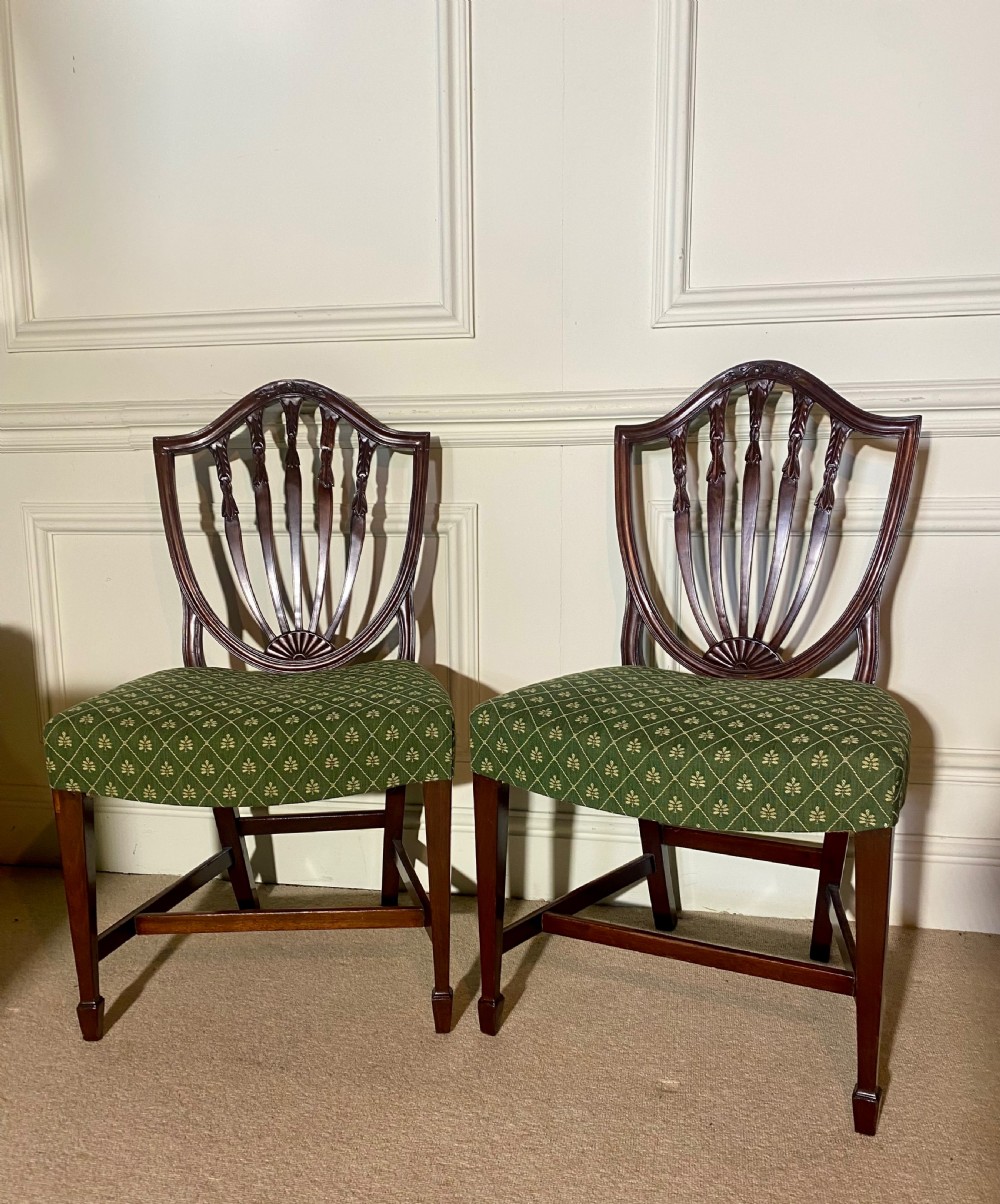 A pair of mahogany Hepplewhite style side chairs featuring carved shield backs and green patterned upholstered seats. View II