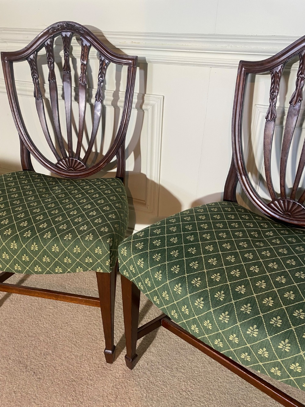A pair of mahogany Hepplewhite style side chairs featuring carved shield backs and green patterned upholstered seats. View III