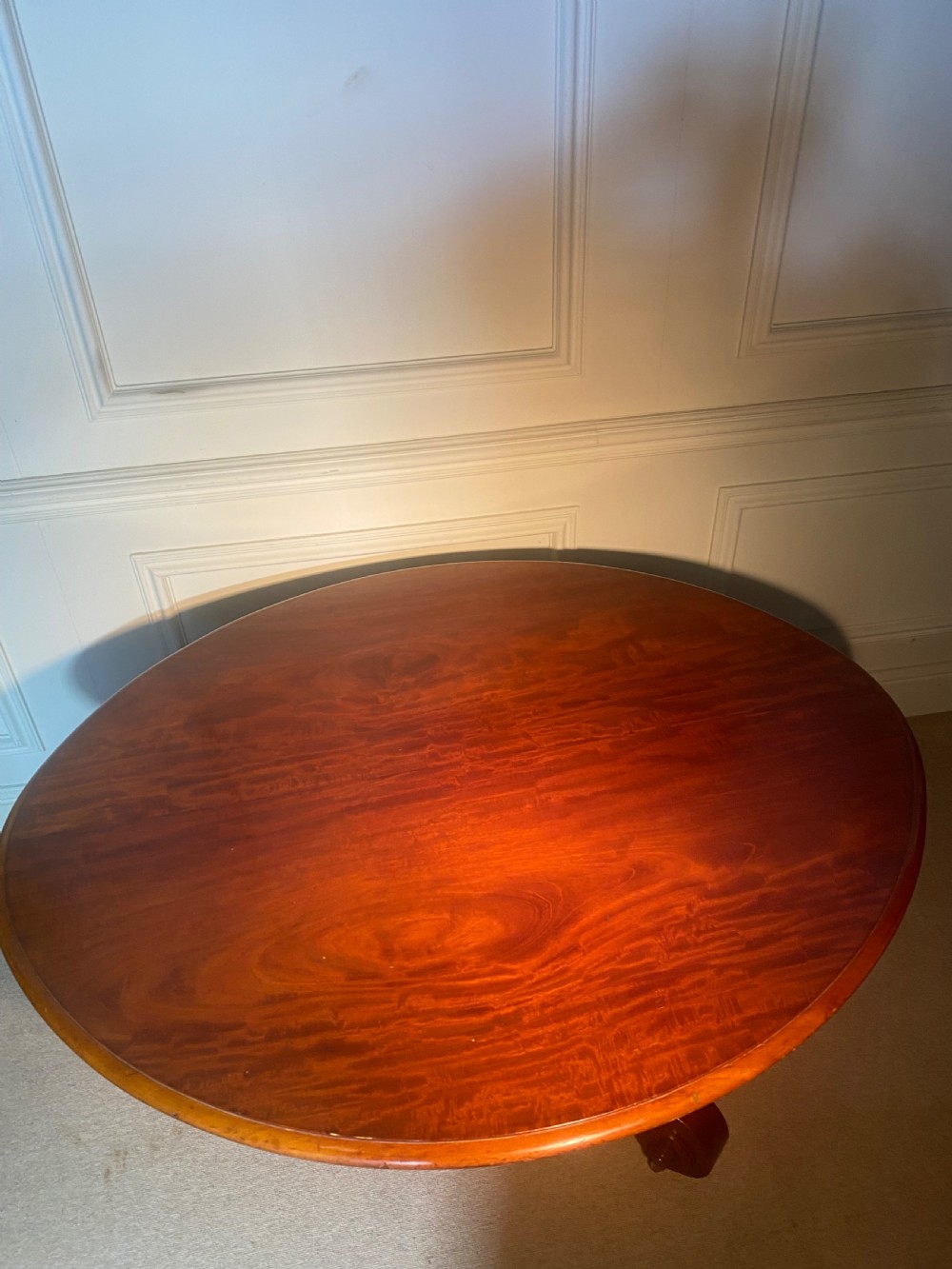 An antique Regency mahogany oval breakfast table featuring a carved fluted pedestal support and scroll feet with brass castors. View XIV
