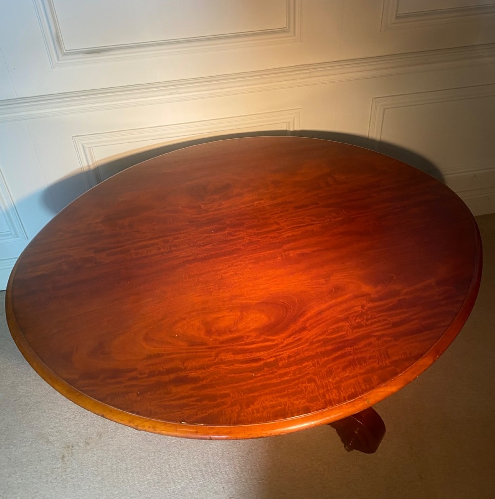 An antique Regency mahogany oval breakfast table featuring a carved fluted pedestal support and scroll feet with brass castors. View XV
