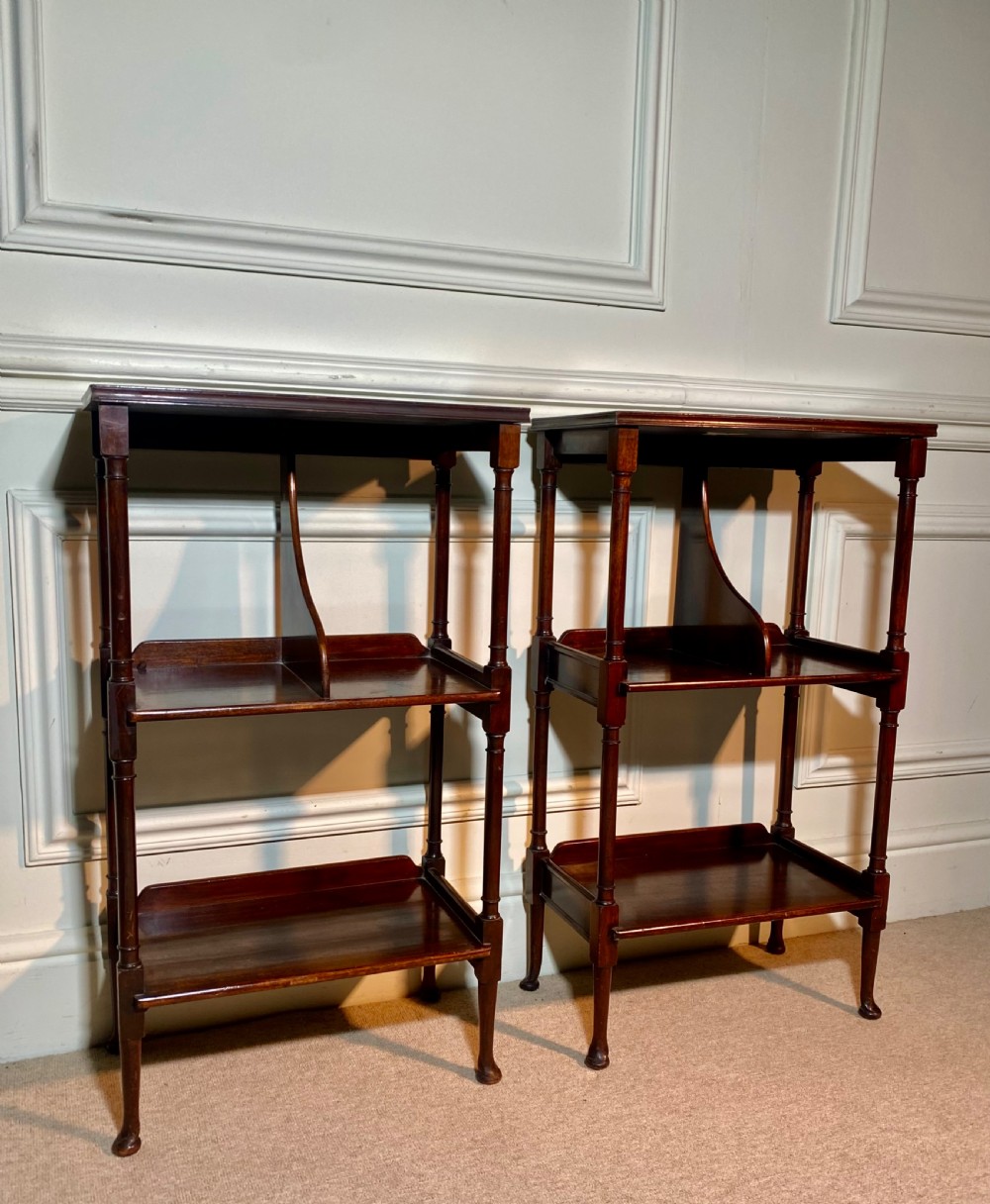 A pair of dark mahogany three-tier open bedside tables with turned supports and pad feet.