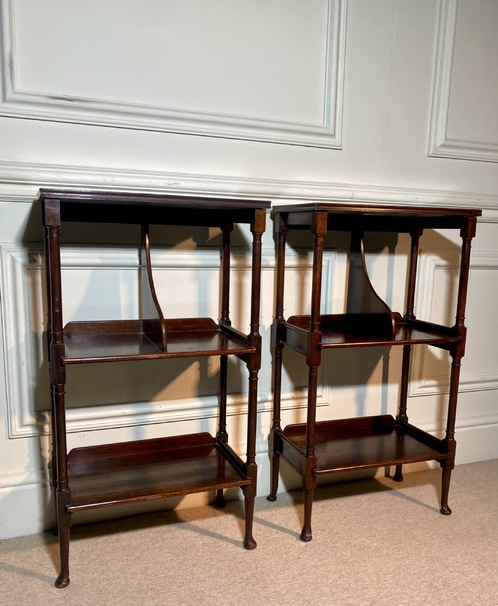 A pair of dark mahogany three-tier open bedside tables with turned supports and pad feet. View II