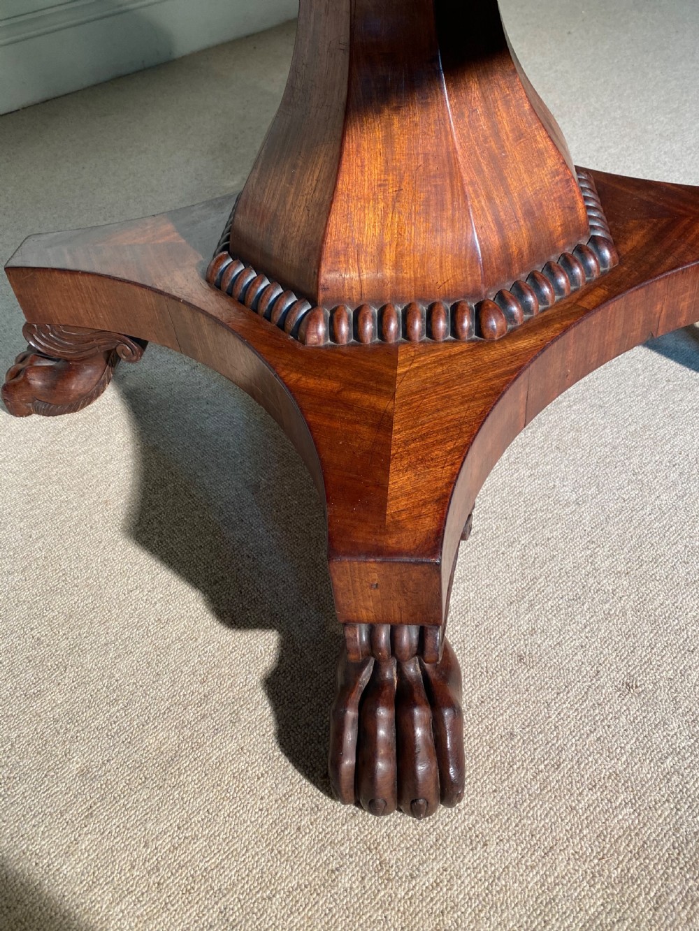 A Regency mahogany hexagonal centre table with a faceted pedestal support and carved lion paw feet. View III