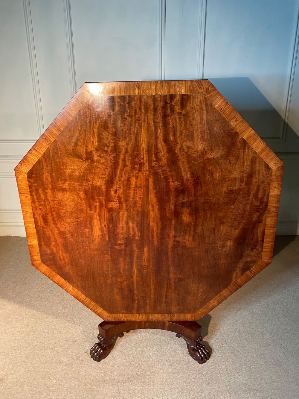 A Regency mahogany hexagonal centre table with a faceted pedestal support and carved lion paw feet. View V