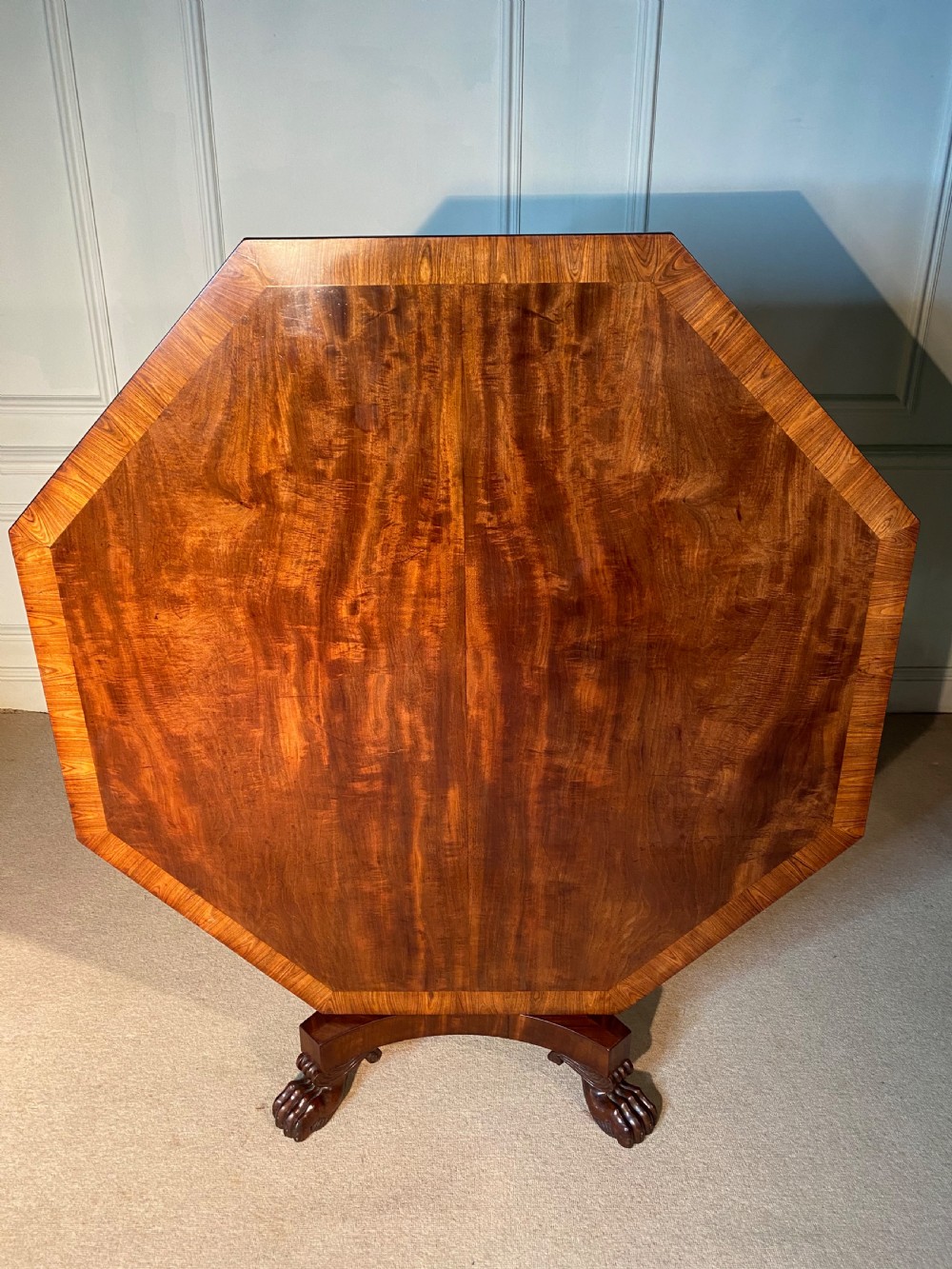 A Regency mahogany hexagonal centre table with a faceted pedestal support and carved lion paw feet. View VI