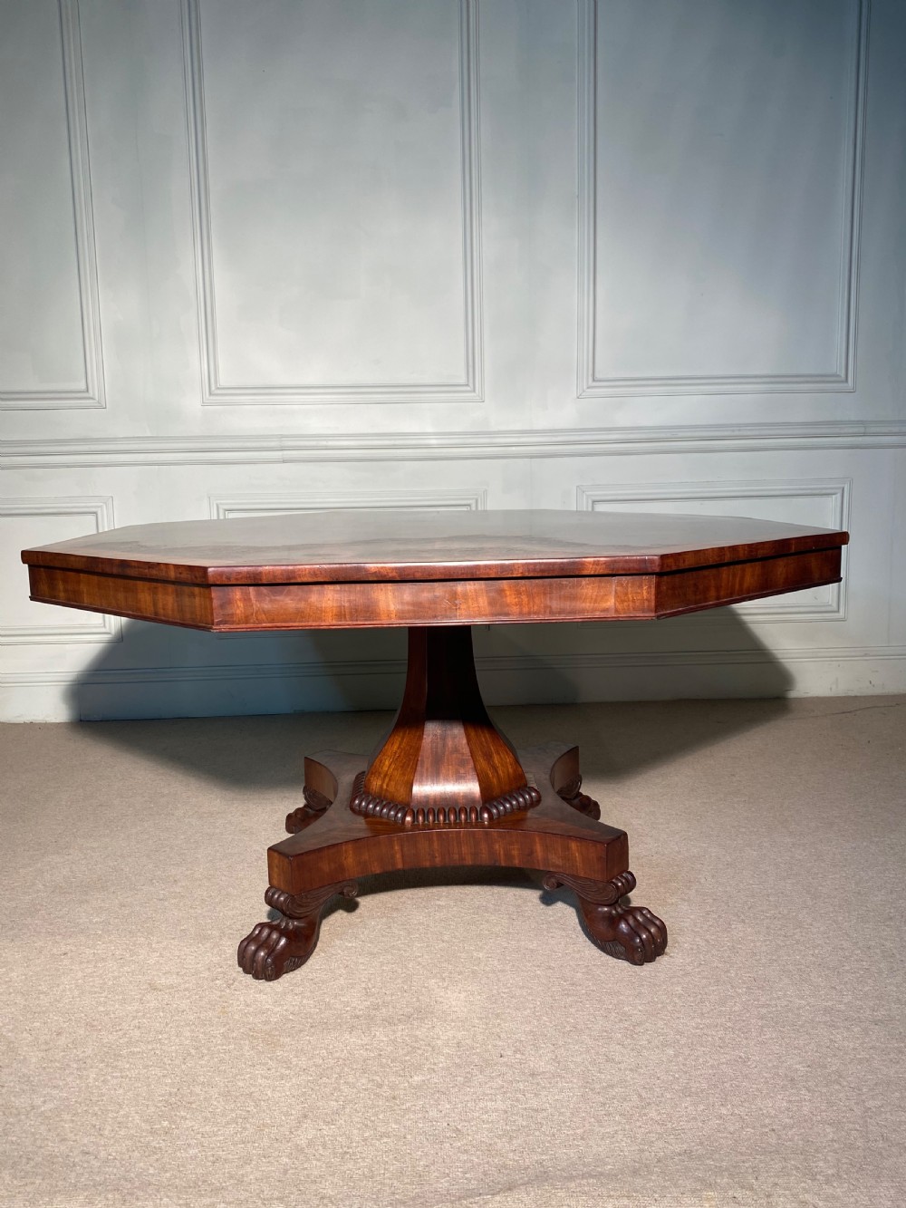 A Regency mahogany hexagonal centre table with a faceted pedestal support and carved lion paw feet. View VIII