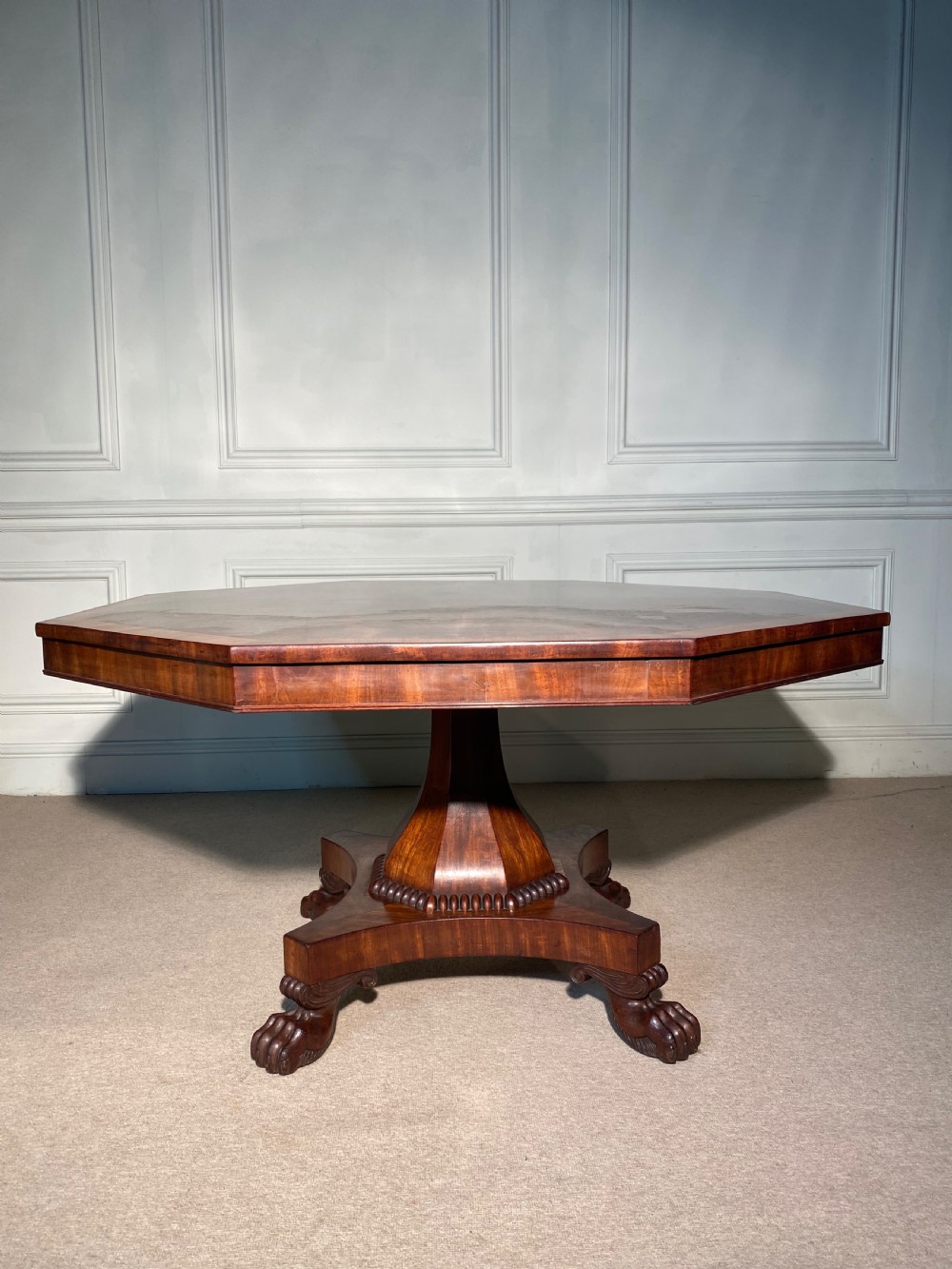 A Regency mahogany hexagonal centre table with a faceted pedestal support and carved lion paw feet. View IX