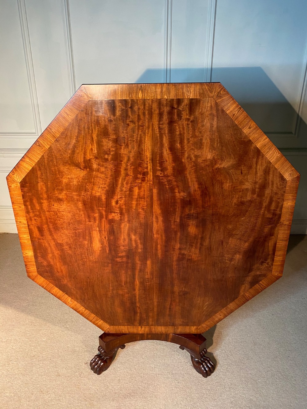 A Regency mahogany hexagonal centre table with a faceted pedestal support and carved lion paw feet. View X