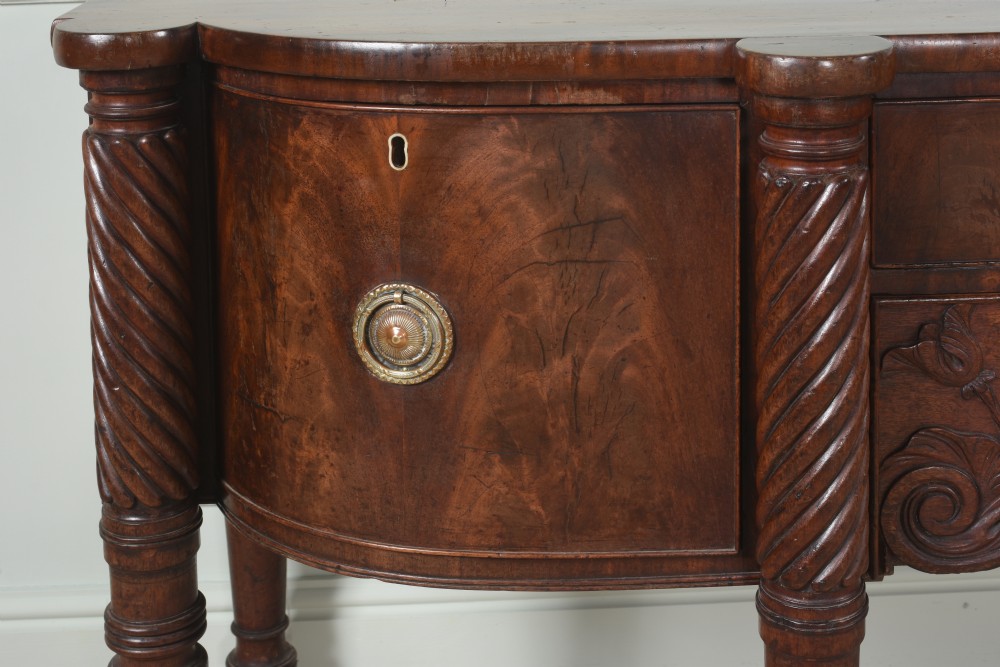 An antique Regency flame mahogany sideboard featuring spiral-turned legs, carved spandrels, multiple drawers, and brass ring handles. View III