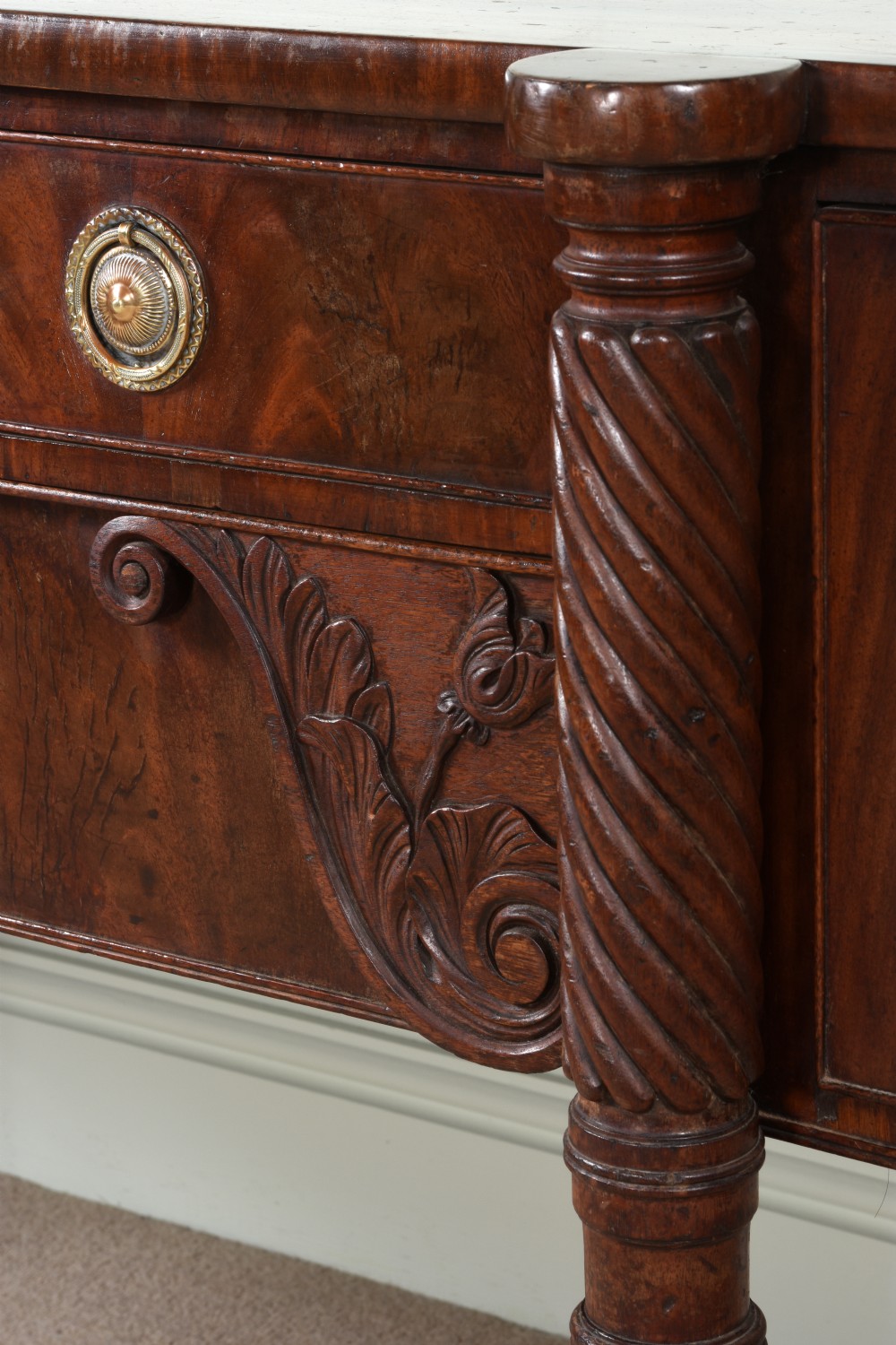An antique Regency flame mahogany sideboard featuring spiral-turned legs, carved spandrels, multiple drawers, and brass ring handles. View VII