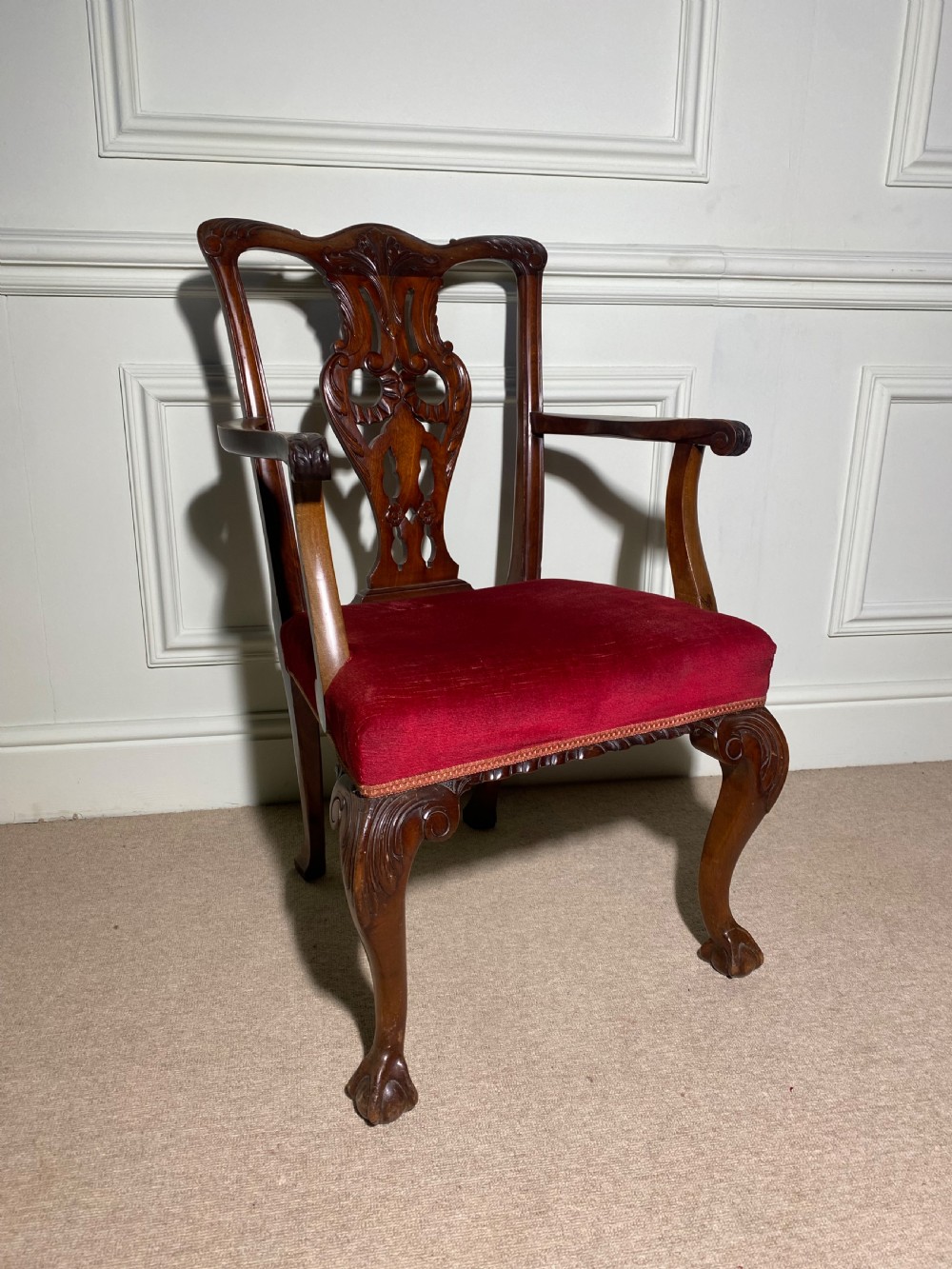 A Chippendale style carved mahogany carver chair featuring a pierced splat back, shaped scroll arms, red velvet seat cushion, and cabriole legs with ball and claw feet. View II