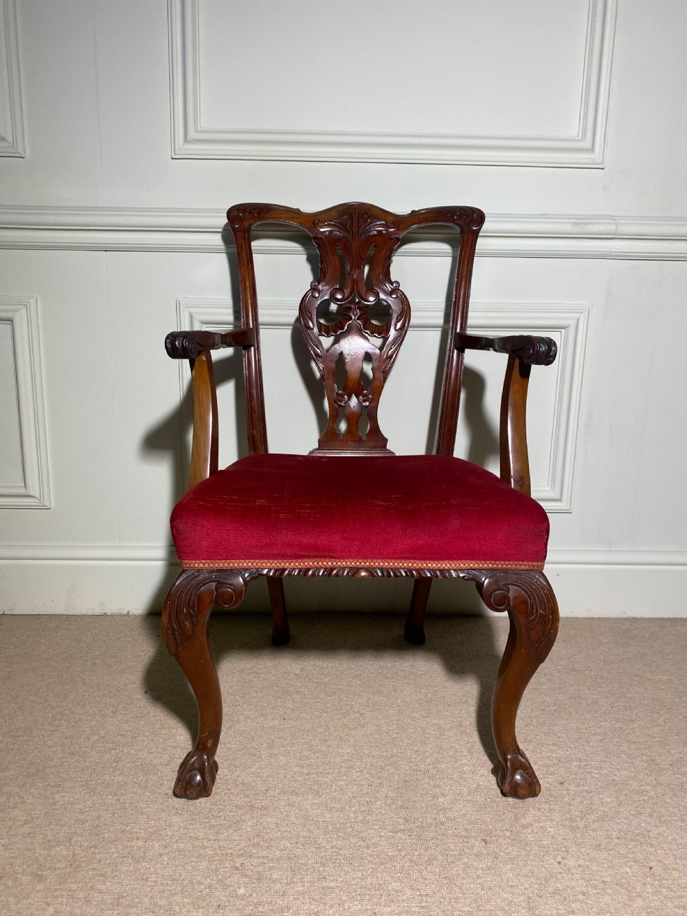 A Chippendale style carved mahogany carver chair featuring a pierced splat back, shaped scroll arms, red velvet seat cushion, and cabriole legs with ball and claw feet. View III