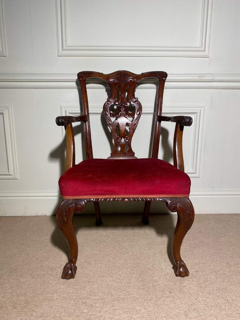 A Chippendale style carved mahogany carver chair featuring a pierced splat back, shaped scroll arms, red velvet seat cushion, and cabriole legs with ball and claw feet. View VI