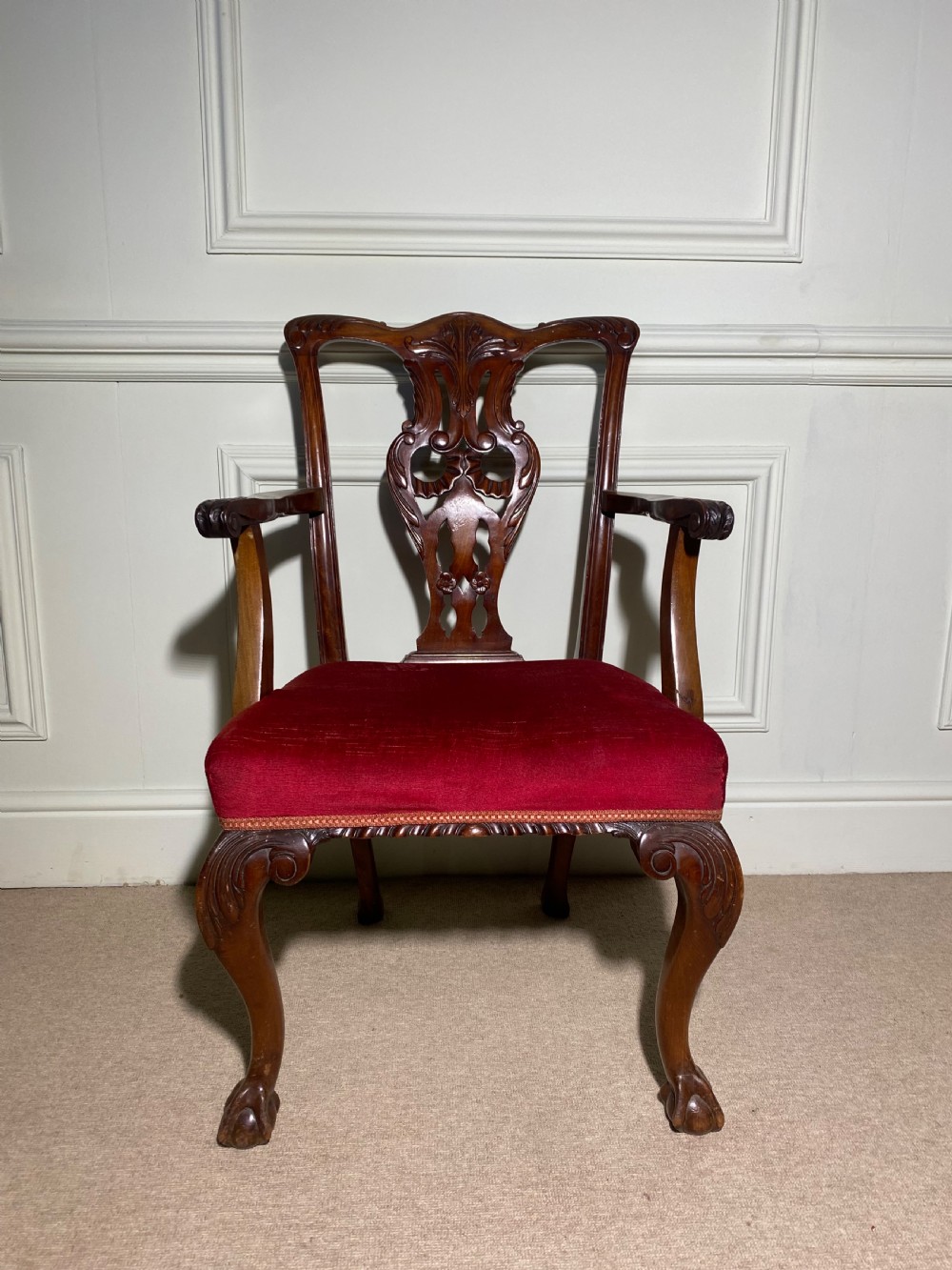 A Chippendale style carved mahogany carver chair featuring a pierced splat back, shaped scroll arms, red velvet seat cushion, and cabriole legs with ball and claw feet. View VII