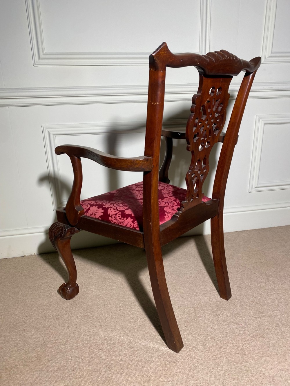 A Chippendale style carved mahogany carver chair featuring a pierced splat back, shaped scroll arms, red velvet seat cushion, and cabriole legs with ball and claw feet. View VIII