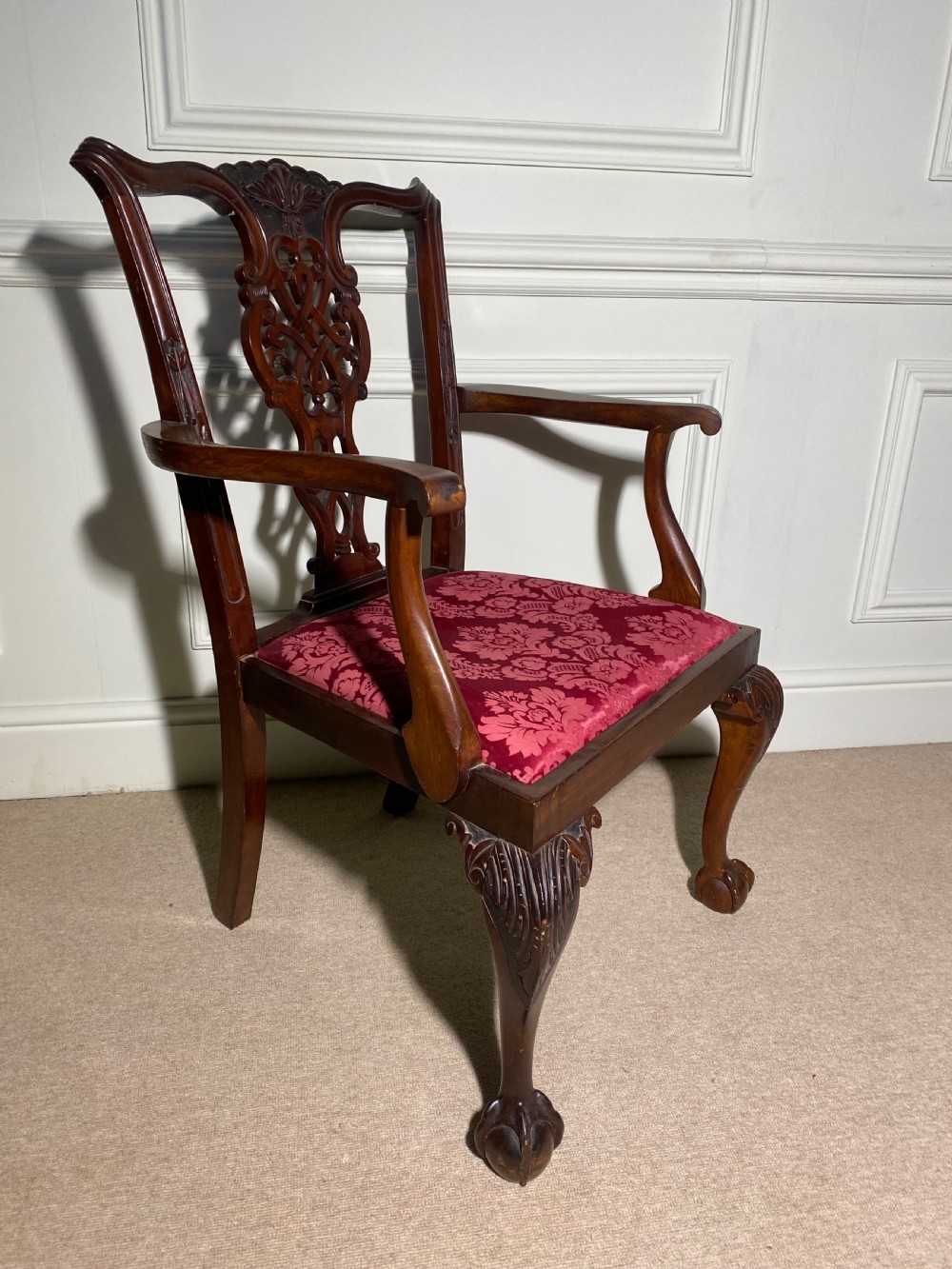 A Chippendale style mahogany carver armchair featuring an intricately carved pierced splat back, red patterned damask upholstery, and cabriole legs with ball and claw feet. View III