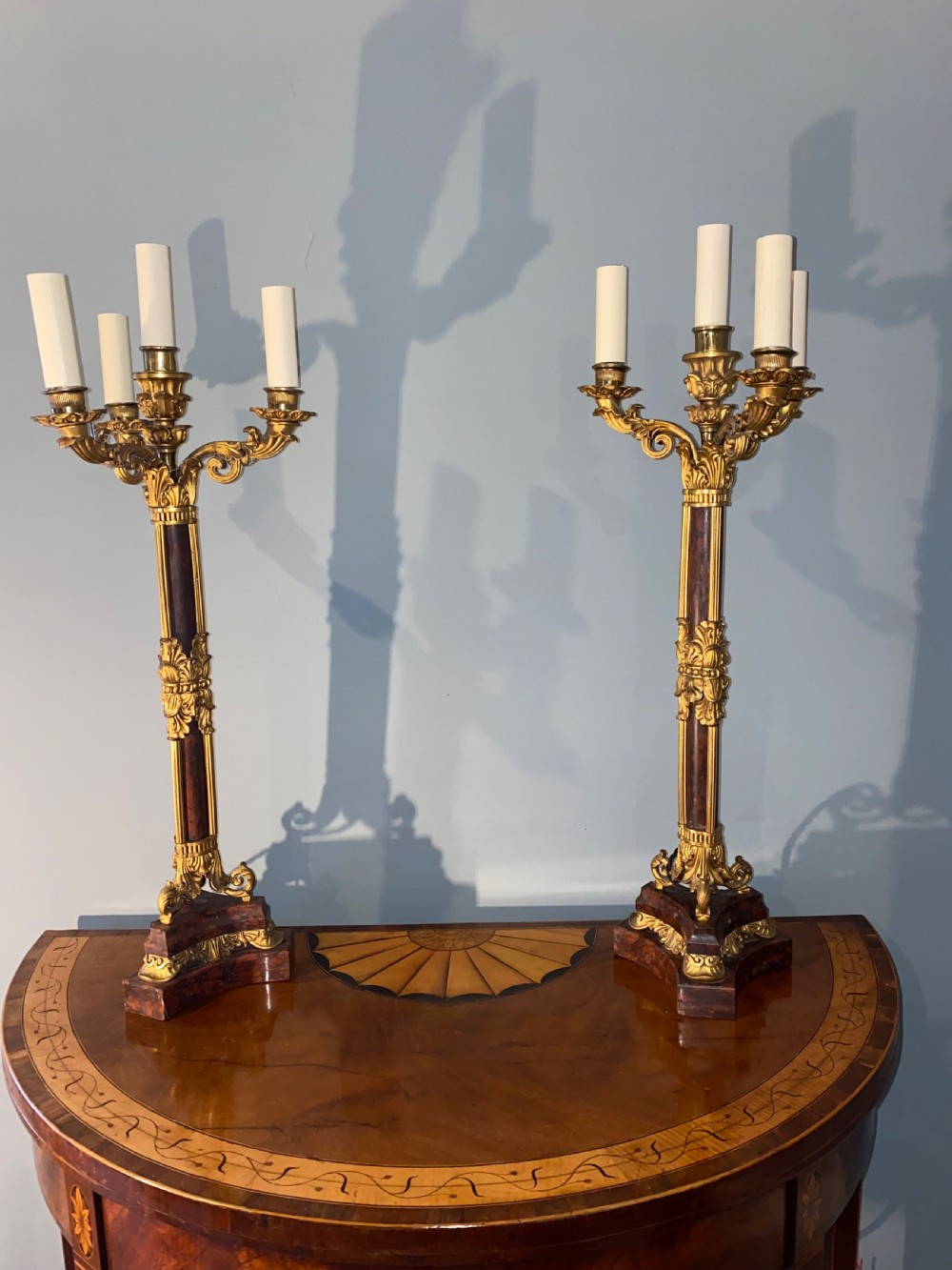 A pair of Neoclassical style gilt bronze and red marble candelabra table lamps featuring scroll arms and candle sockets.