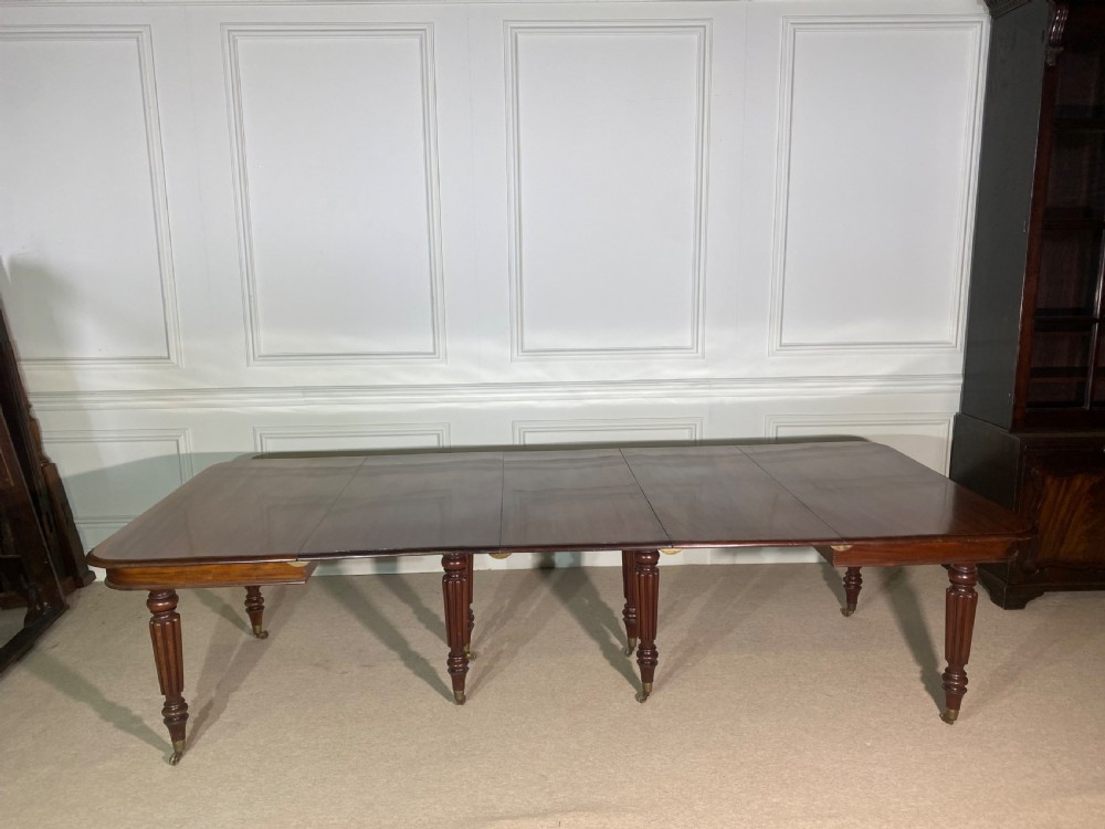 A large Regency mahogany extending dining table with insertable leaves, resting on turned reeded legs with brass castors.