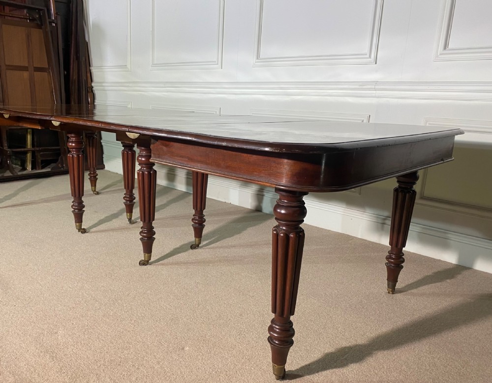 A large Regency mahogany extending dining table with insertable leaves, resting on turned reeded legs with brass castors. View V