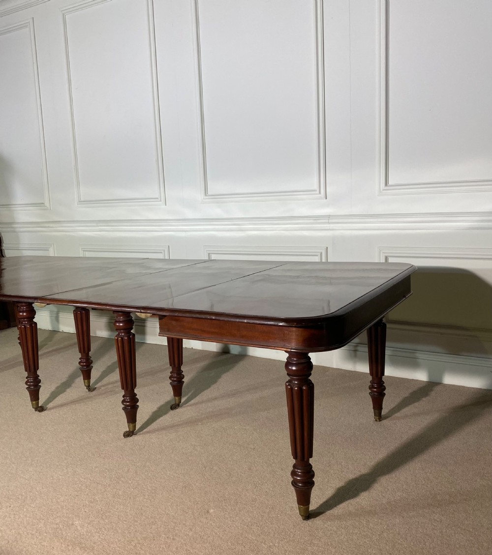 A large Regency mahogany extending dining table with insertable leaves, resting on turned reeded legs with brass castors. View VI