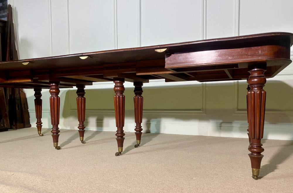 A large Regency mahogany extending dining table with insertable leaves, resting on turned reeded legs with brass castors. View VII