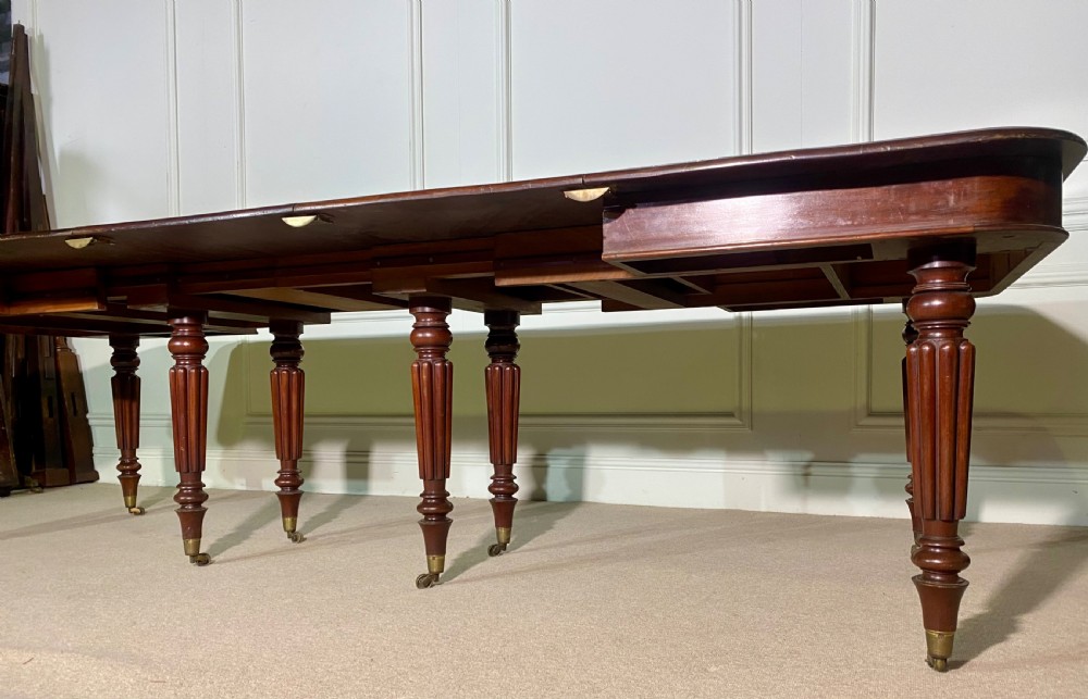 A large Regency mahogany extending dining table with insertable leaves, resting on turned reeded legs with brass castors. View VIII