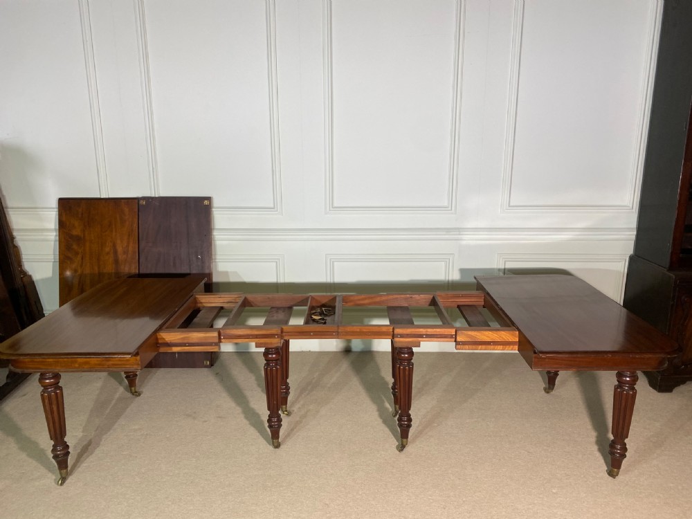 A large Regency mahogany extending dining table with insertable leaves, resting on turned reeded legs with brass castors. View XII