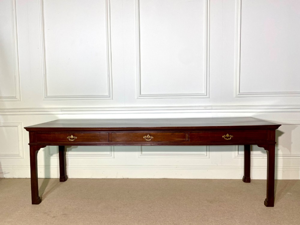 A long Georgian mahogany serving table featuring three frieze drawers with brass swan-neck handles and straight square legs.
