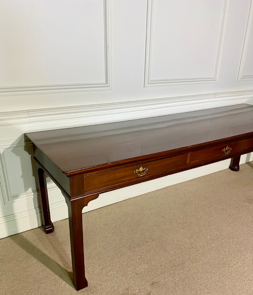 A long Georgian mahogany serving table featuring three frieze drawers with brass swan-neck handles and straight square legs. View II