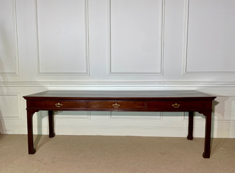 A long Georgian mahogany serving table featuring three frieze drawers with brass swan-neck handles and straight square legs. View V