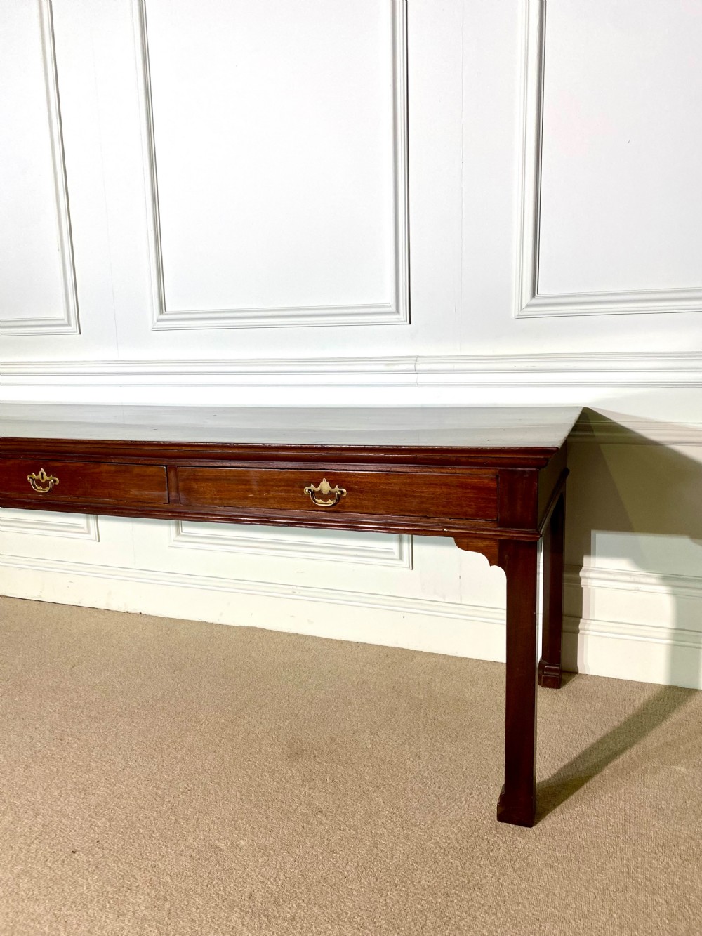 A long Georgian mahogany serving table featuring three frieze drawers with brass swan-neck handles and straight square legs. View VI