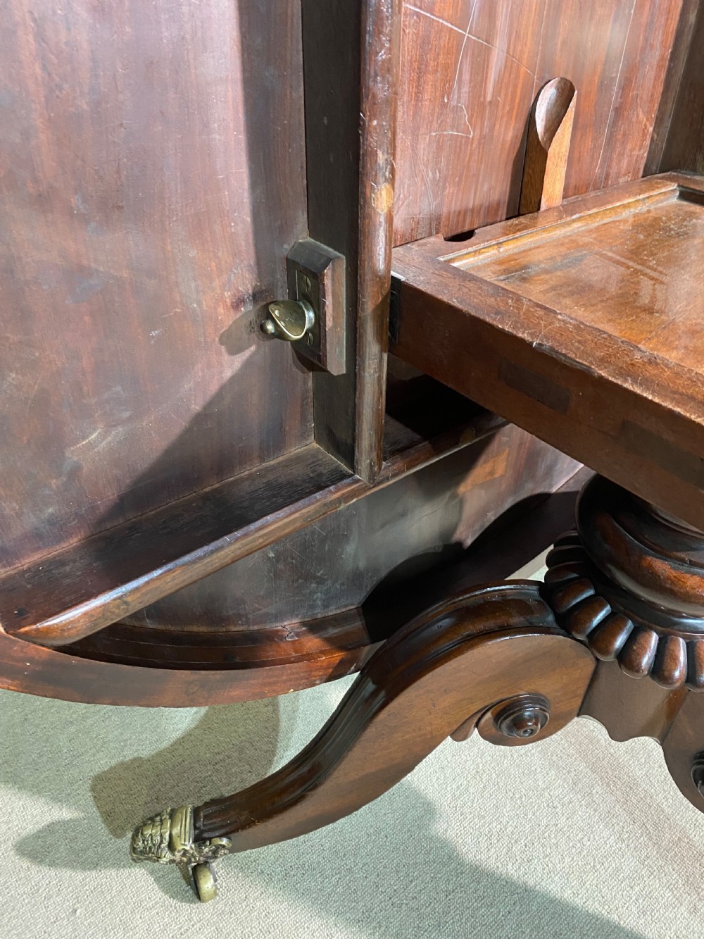 A circular Regency mahogany centre table featuring a polished top supported by a central column and splayed legs ending in brass lion paw castors. View V