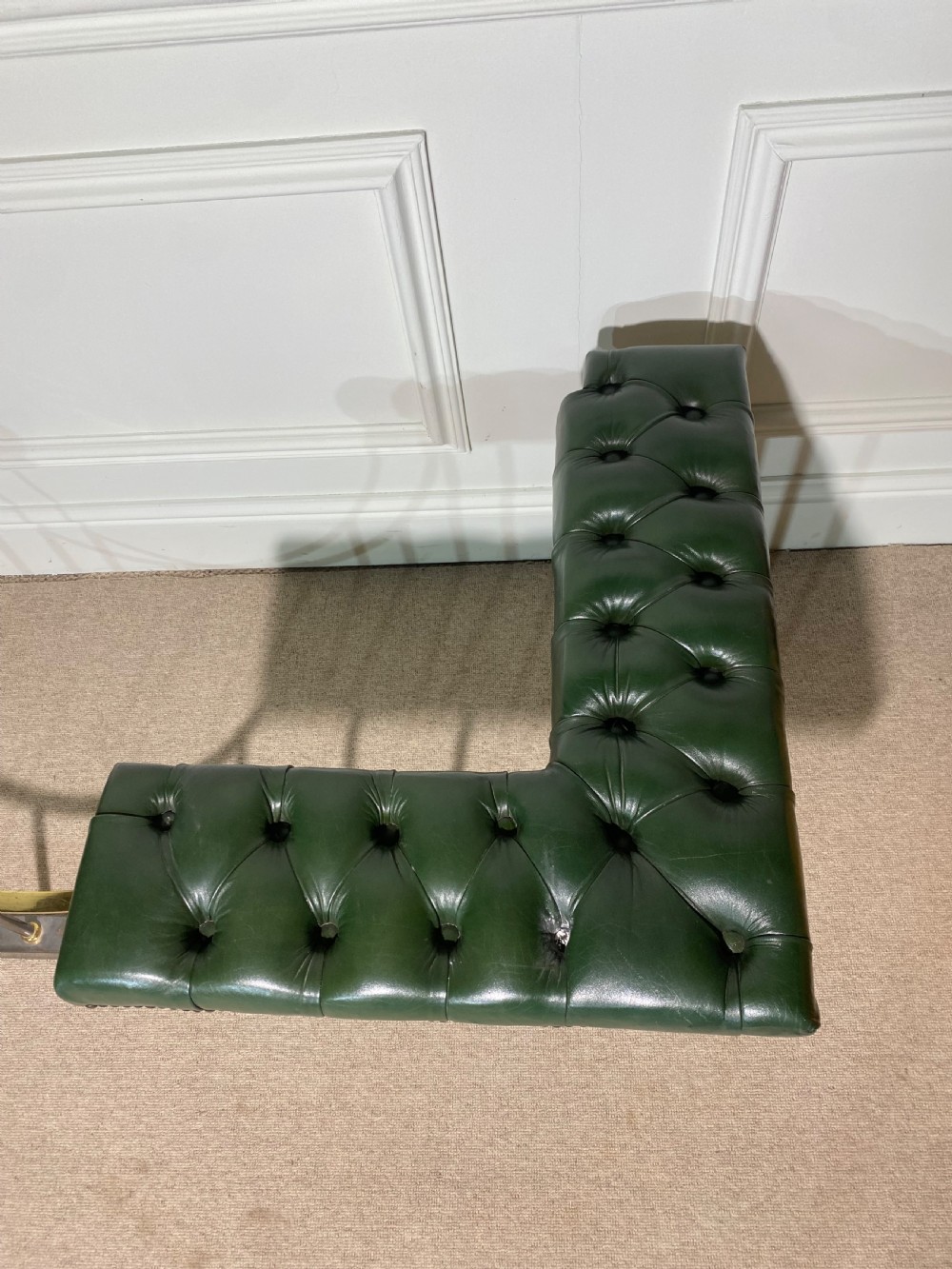 A metal fireplace club fender with vertical steel uprights, brass accents, a central curved dip, and two corner seats upholstered in button-tufted dark green leather with brass studding. View II