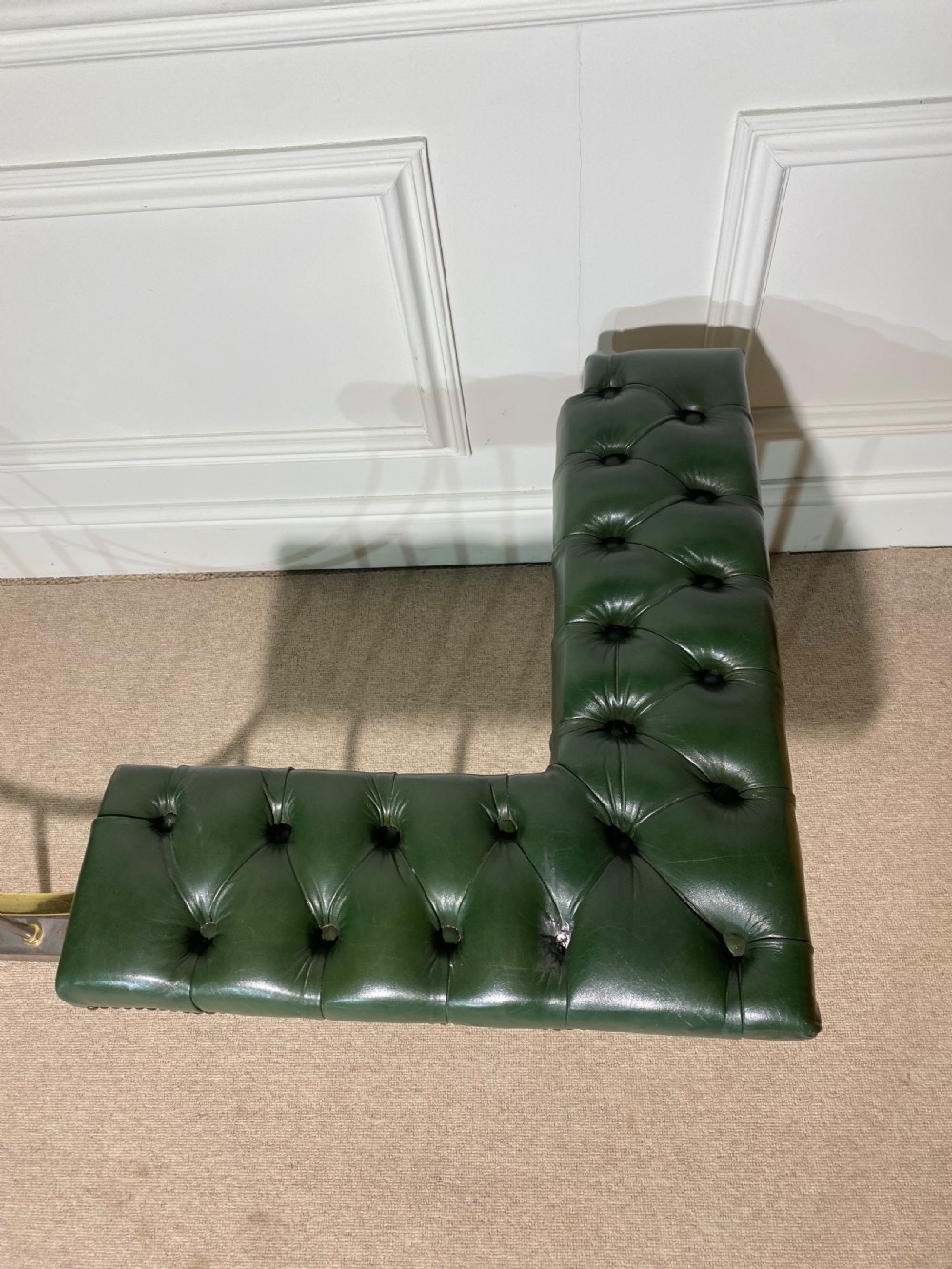 A metal fireplace club fender with vertical steel uprights, brass accents, a central curved dip, and two corner seats upholstered in button-tufted dark green leather with brass studding. View III
