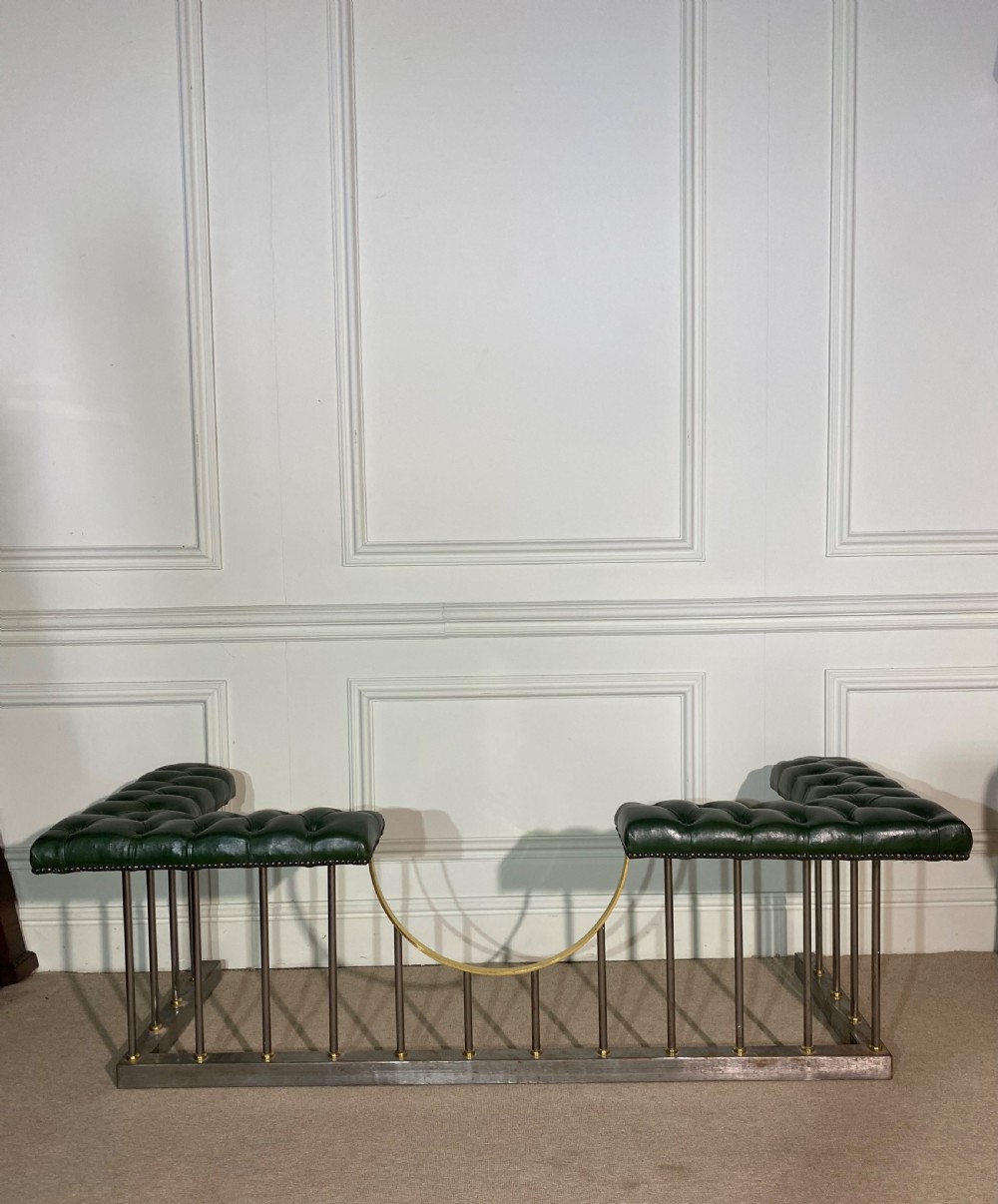 A metal fireplace club fender with vertical steel uprights, brass accents, a central curved dip, and two corner seats upholstered in button-tufted dark green leather with brass studding. View VII