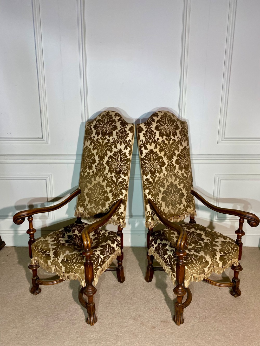 A pair of high-back Carolean style armchairs upholstered in patterned brown velvet with fringe trim and carved timber frames. View II