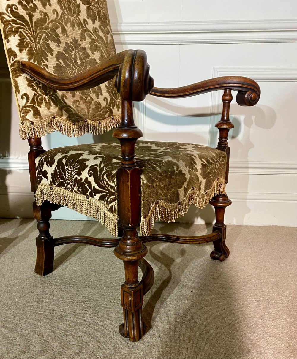 A pair of high-back Carolean style armchairs upholstered in patterned brown velvet with fringe trim and carved timber frames. View III