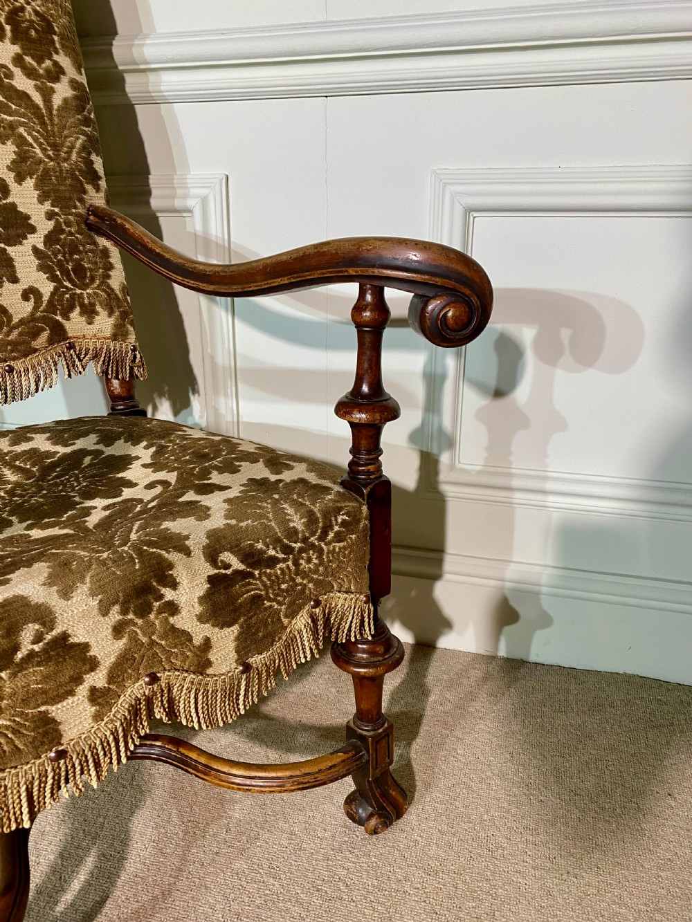 A pair of high-back Carolean style armchairs upholstered in patterned brown velvet with fringe trim and carved timber frames. View V