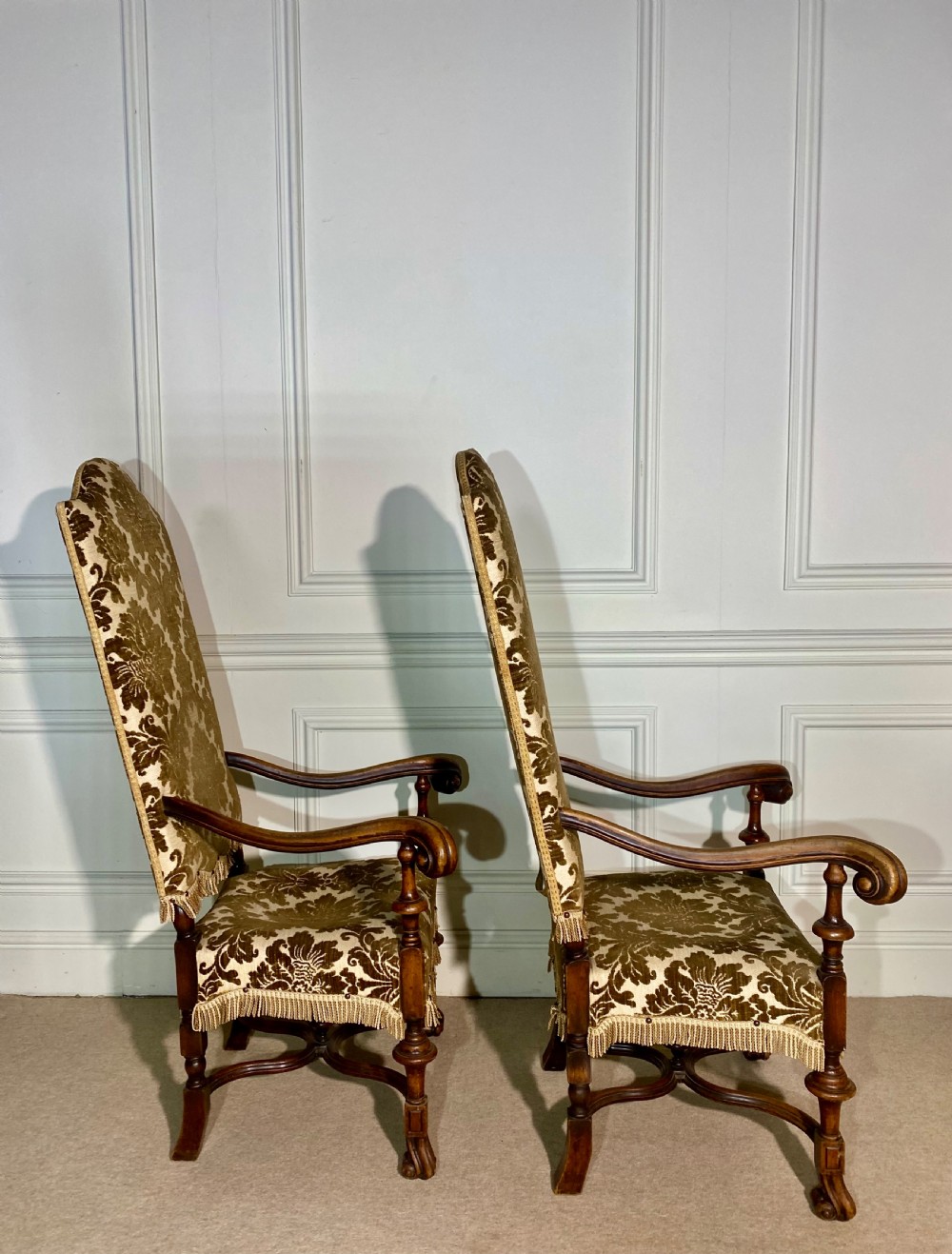 A pair of high-back Carolean style armchairs upholstered in patterned brown velvet with fringe trim and carved timber frames. View VII