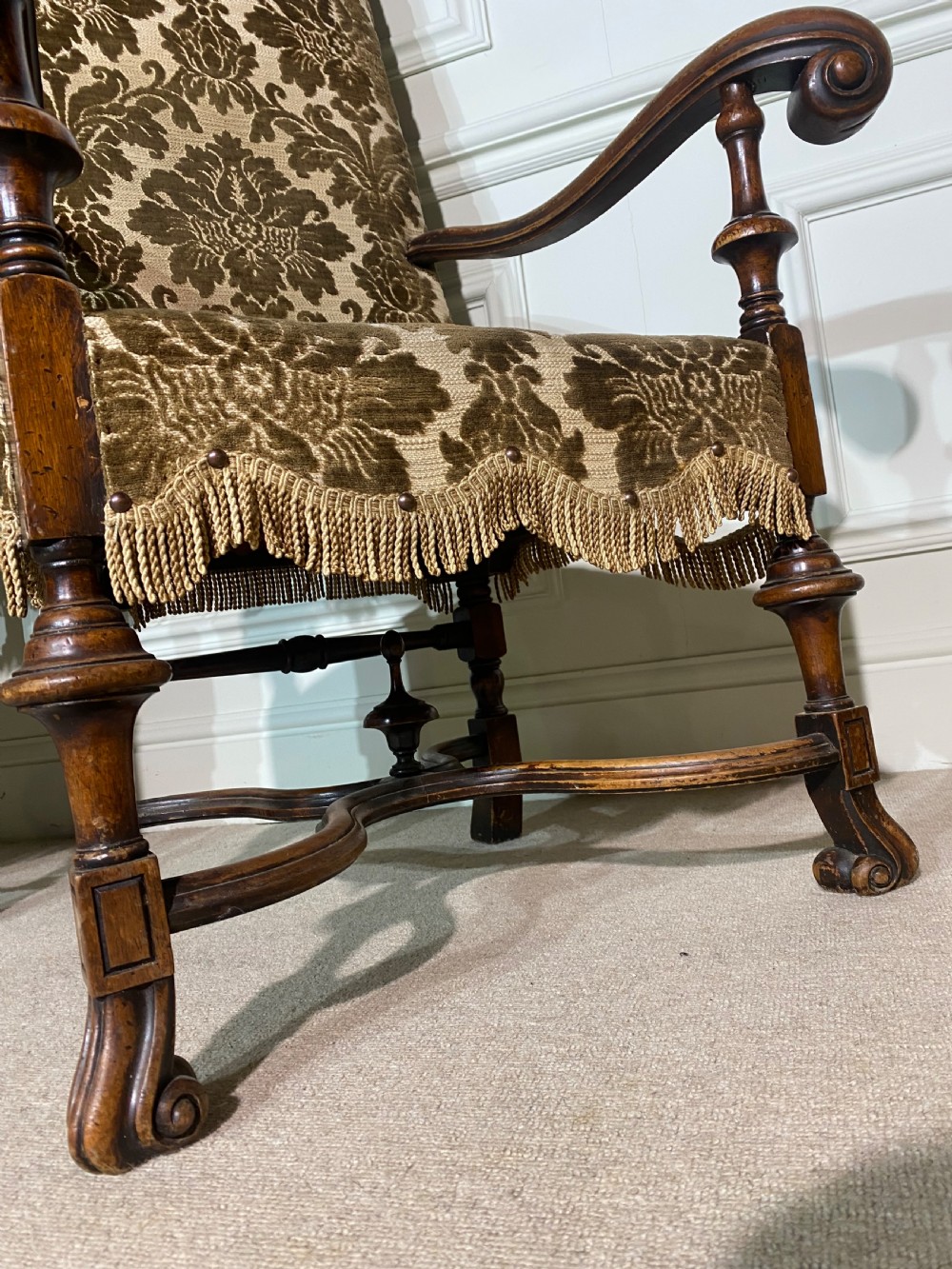 A pair of high-back Carolean style armchairs upholstered in patterned brown velvet with fringe trim and carved timber frames. View X