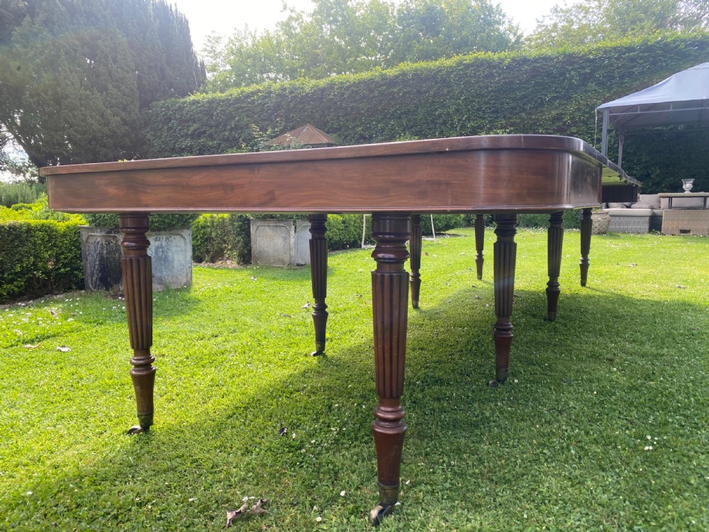 An early nineteenth century Regency mahogany extending dining table featuring reeded turned legs on brass castors. View II