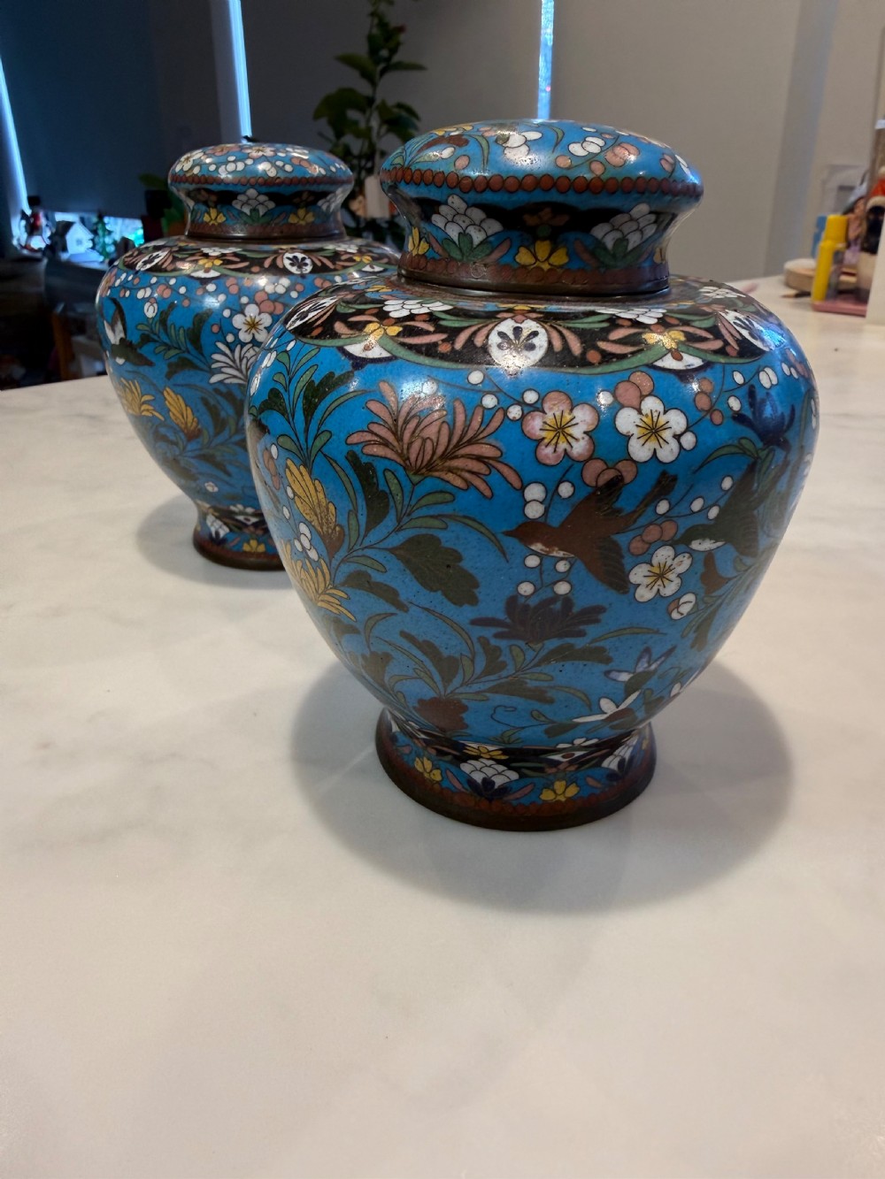 A pair of bulbous Japanese cloisonne ginger jars with lids, featuring intricate floral and bird motifs on a vibrant turquoise blue ground. View III