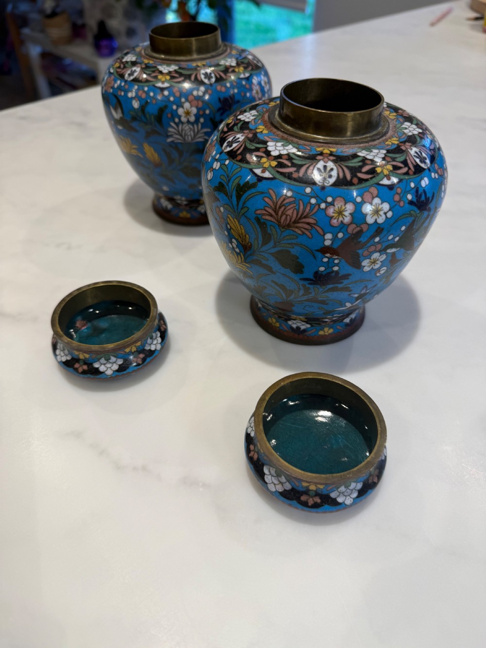 A pair of bulbous Japanese cloisonne ginger jars with lids, featuring intricate floral and bird motifs on a vibrant turquoise blue ground. View VI