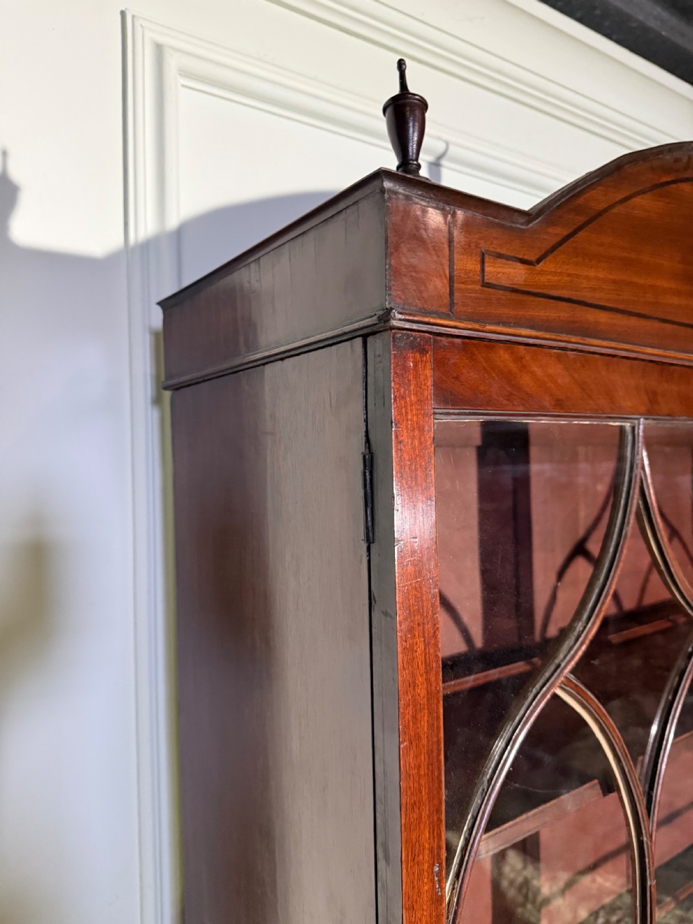 A tall Georgian mahogany secretaire bookcase featuring upper glazed doors with gothic arch bars, an arched pediment with finials, and a lower chest of drawers with brass ring handles. View VII