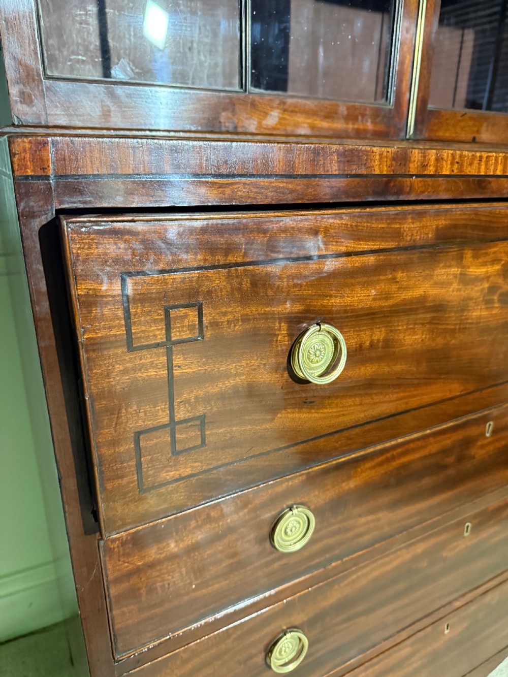 A tall Georgian mahogany secretaire bookcase featuring upper glazed doors with gothic arch bars, an arched pediment with finials, and a lower chest of drawers with brass ring handles. View VIII